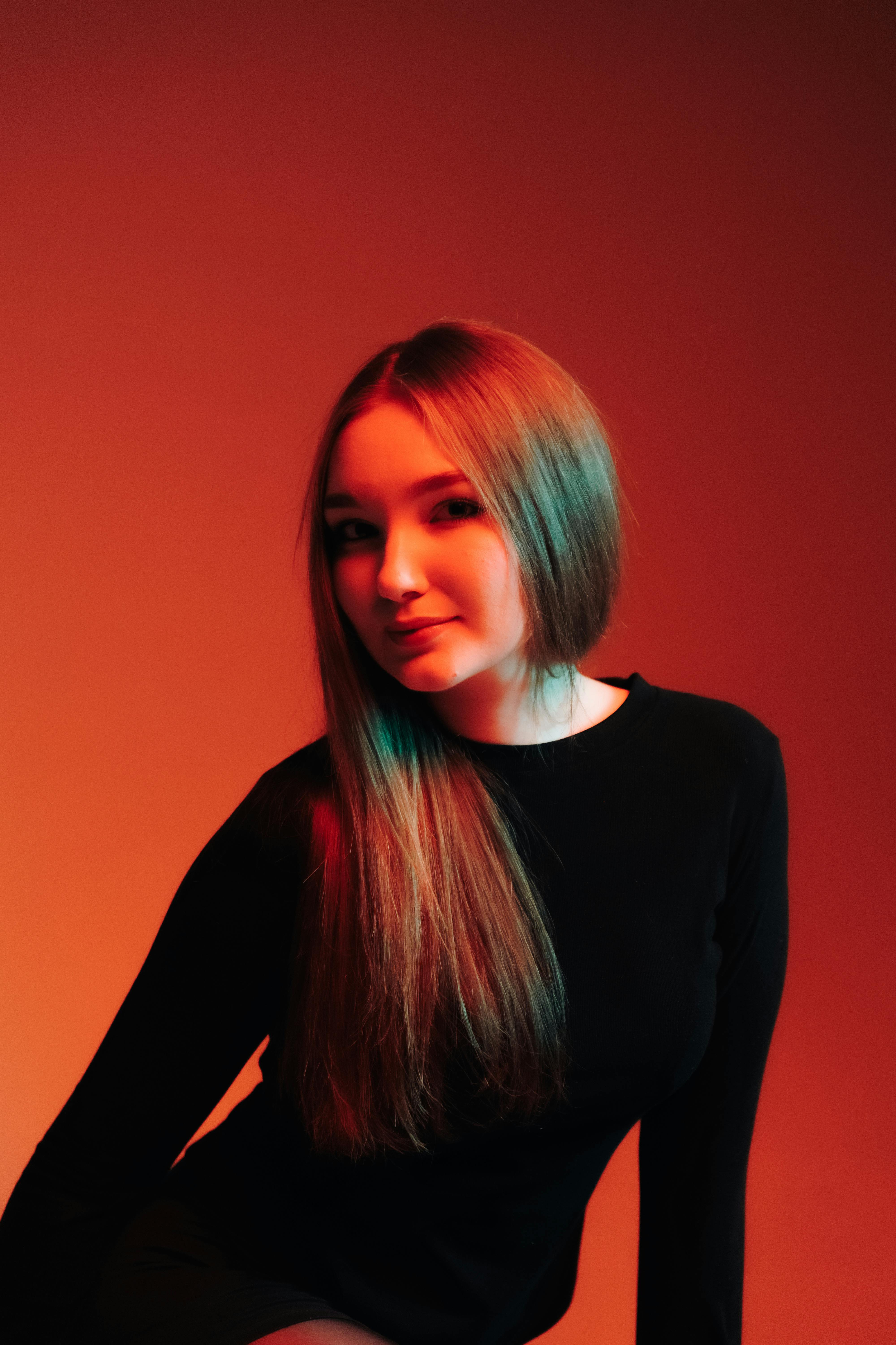 Bezpłatne Artystyczny portret kobiety w dramatycznym oświetleniu w odcieniach czerwieni i błękitu. Zdjęcie z galerii