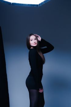 Stylish portrait of a young adult woman posing confidently in a studio with soft lighting.