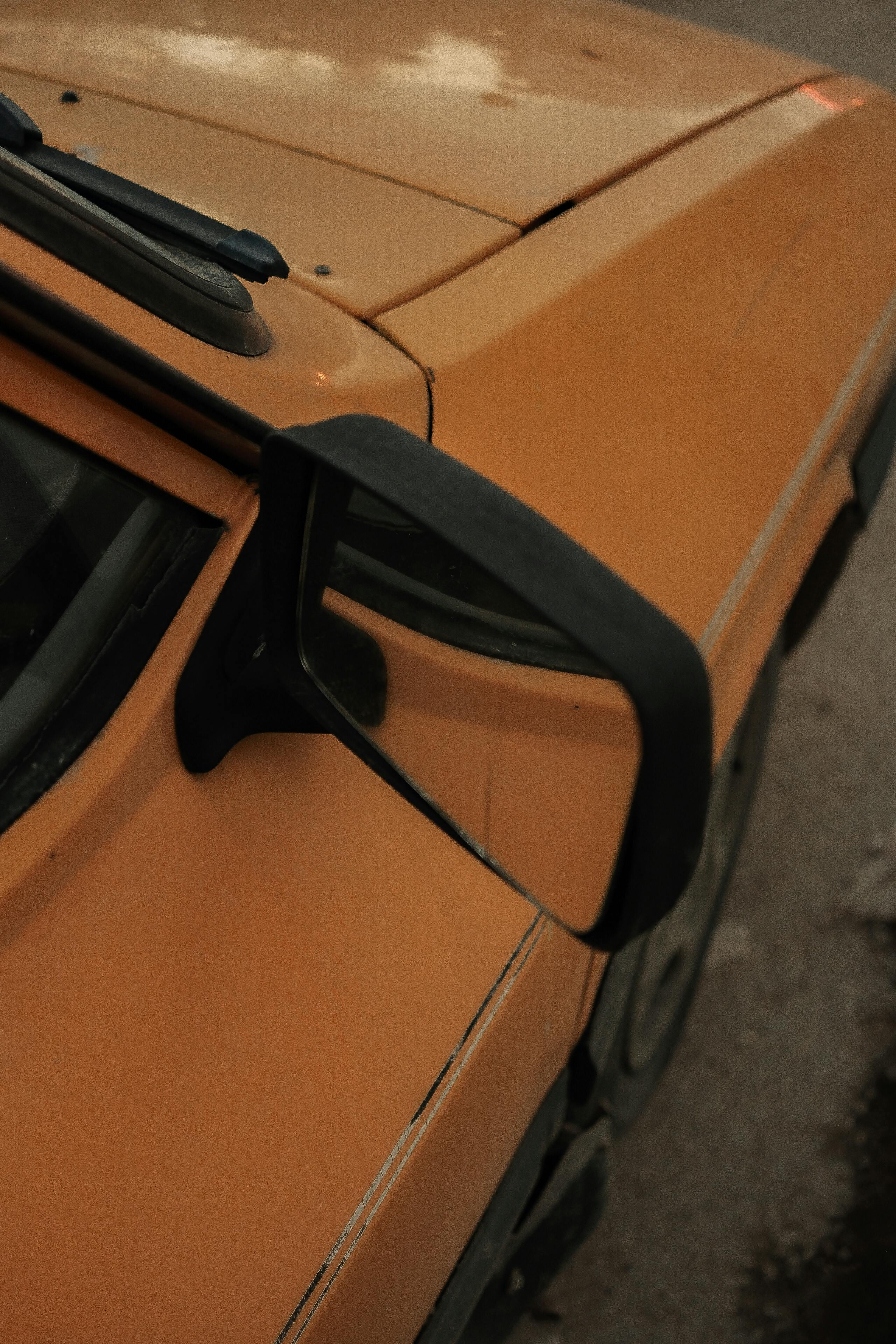 Bezpłatne Szczegółowy widok bocznego lusterka zabytkowego, pomarańczowego samochodu z artystycznym akcentem, idealny do tematyki motoryzacyjnej. Zdjęcie z galerii