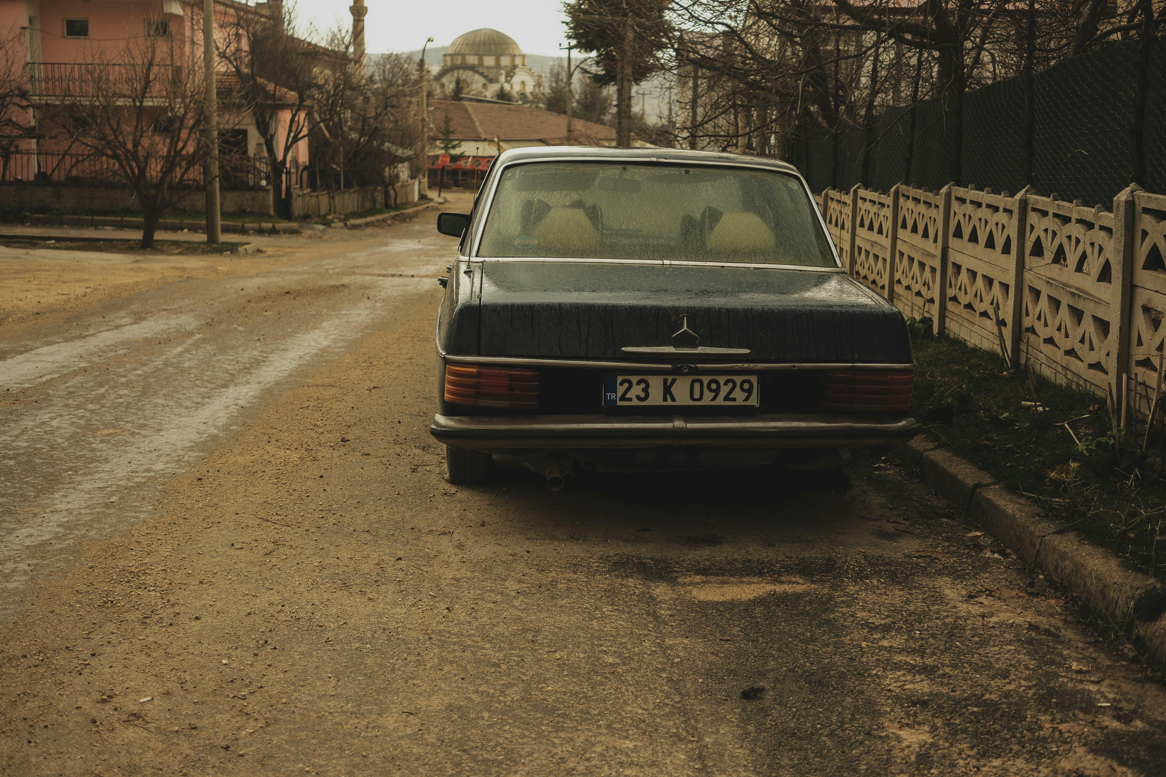 Bezpłatne Zabytkowy samochód zaparkowany na spokojnej ulicy o zimowej atmosferze, otoczony rustykalną architekturą. Zdjęcie z galerii