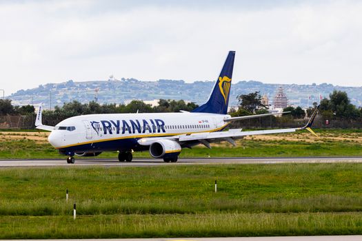 Ryanair airplane taxiing on runway with scenic hilly background.