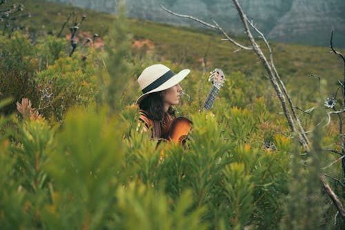 Woman in White Hat and Brown Long Sleeve Shirt on Green Grass Field