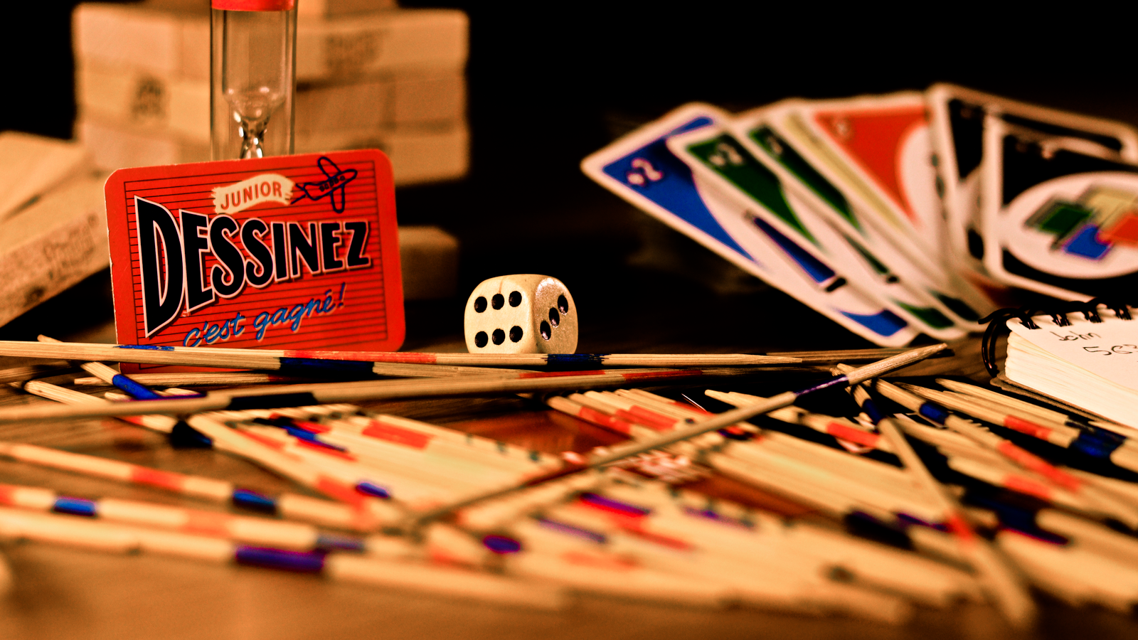 Cards, a die, game pieces and a small timer arranged on a table