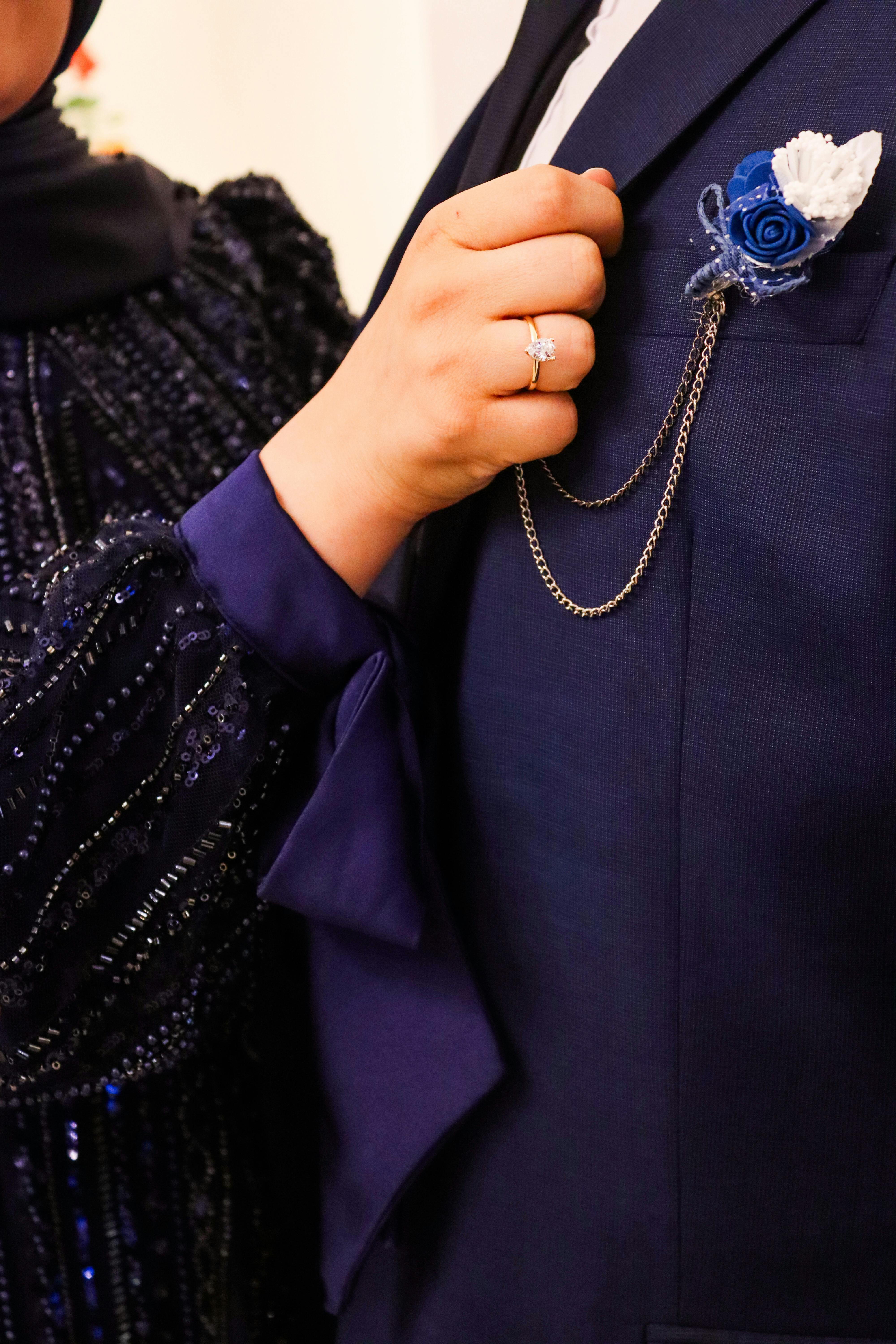 Bezpłatne Zbliżenie pary ubranej w dopasowane niebieskie stroje z kwiatową butonierą, co sugeruje elegancję i formalność. Zdjęcie z galerii