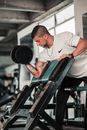 Man in White T-shirt and Gray Pants Holding Black Dumbbell