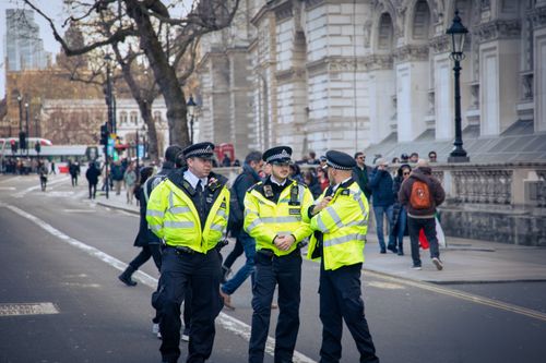 Free Police officers patrolling a busy street in London, showcasing urban security and public safety. Stock Photo