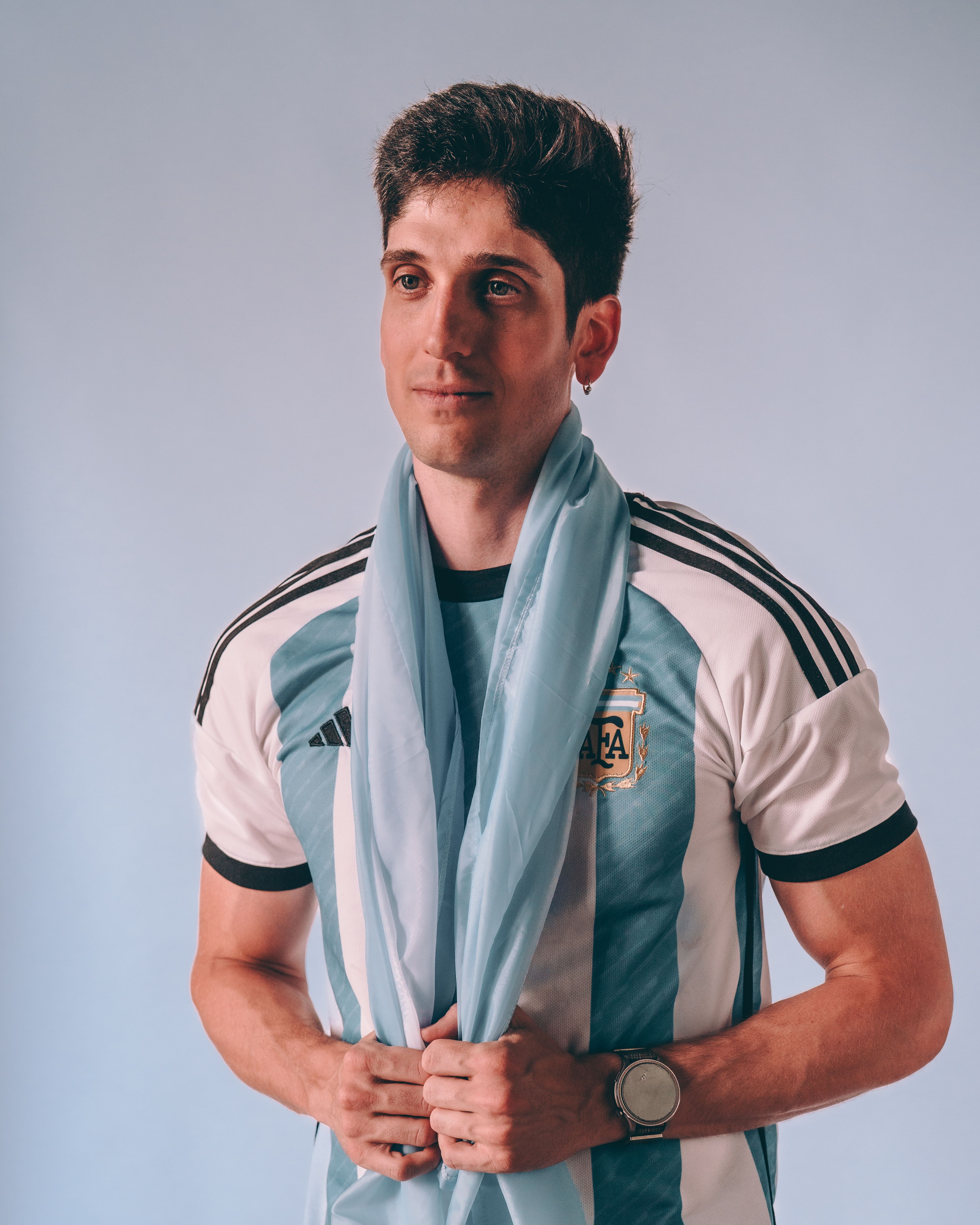 Portrait of a young man wearing an Argentina football jersey with a blue scarf.