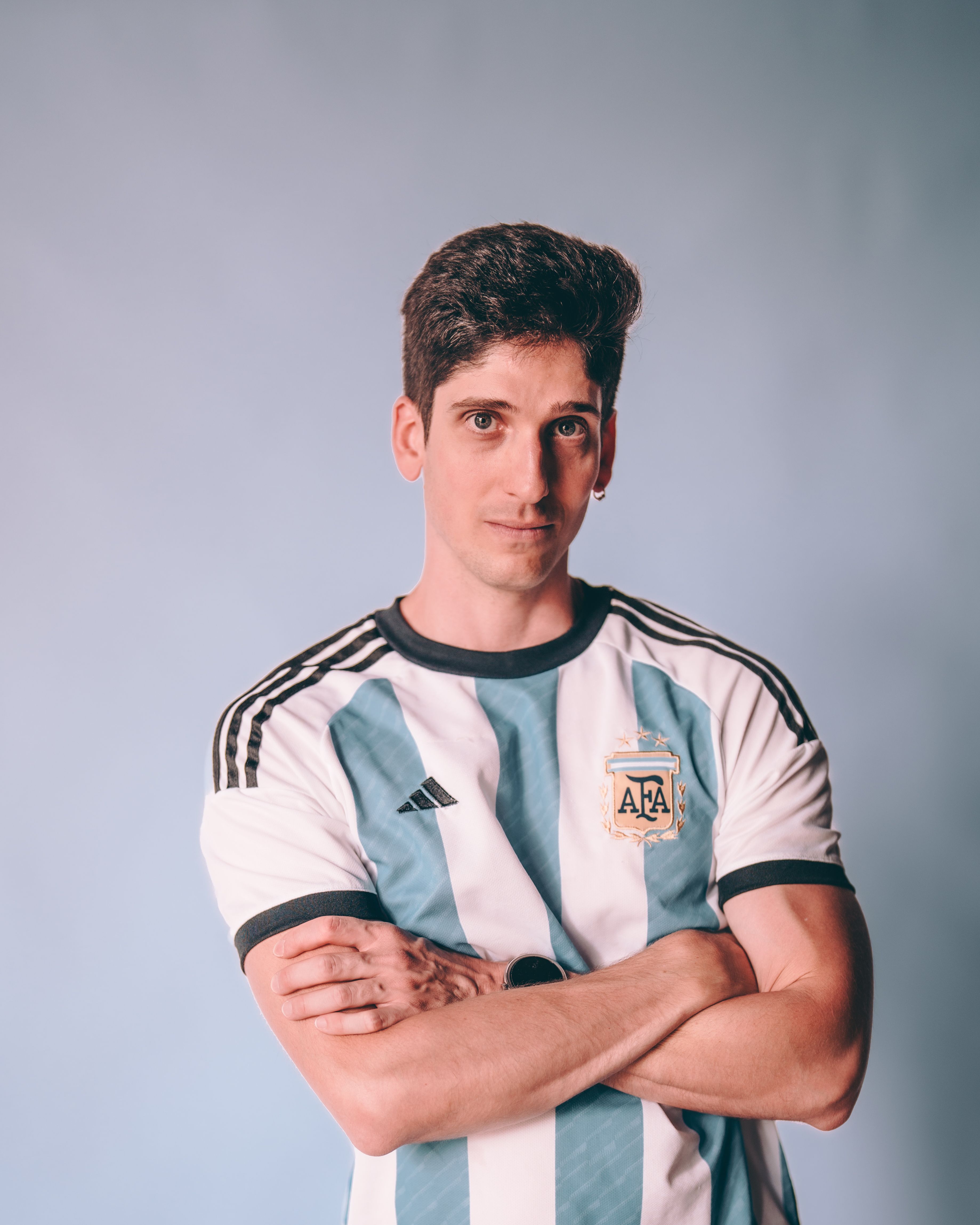 Young man in an Argentina soccer jersey poses confidently against a neutral background.