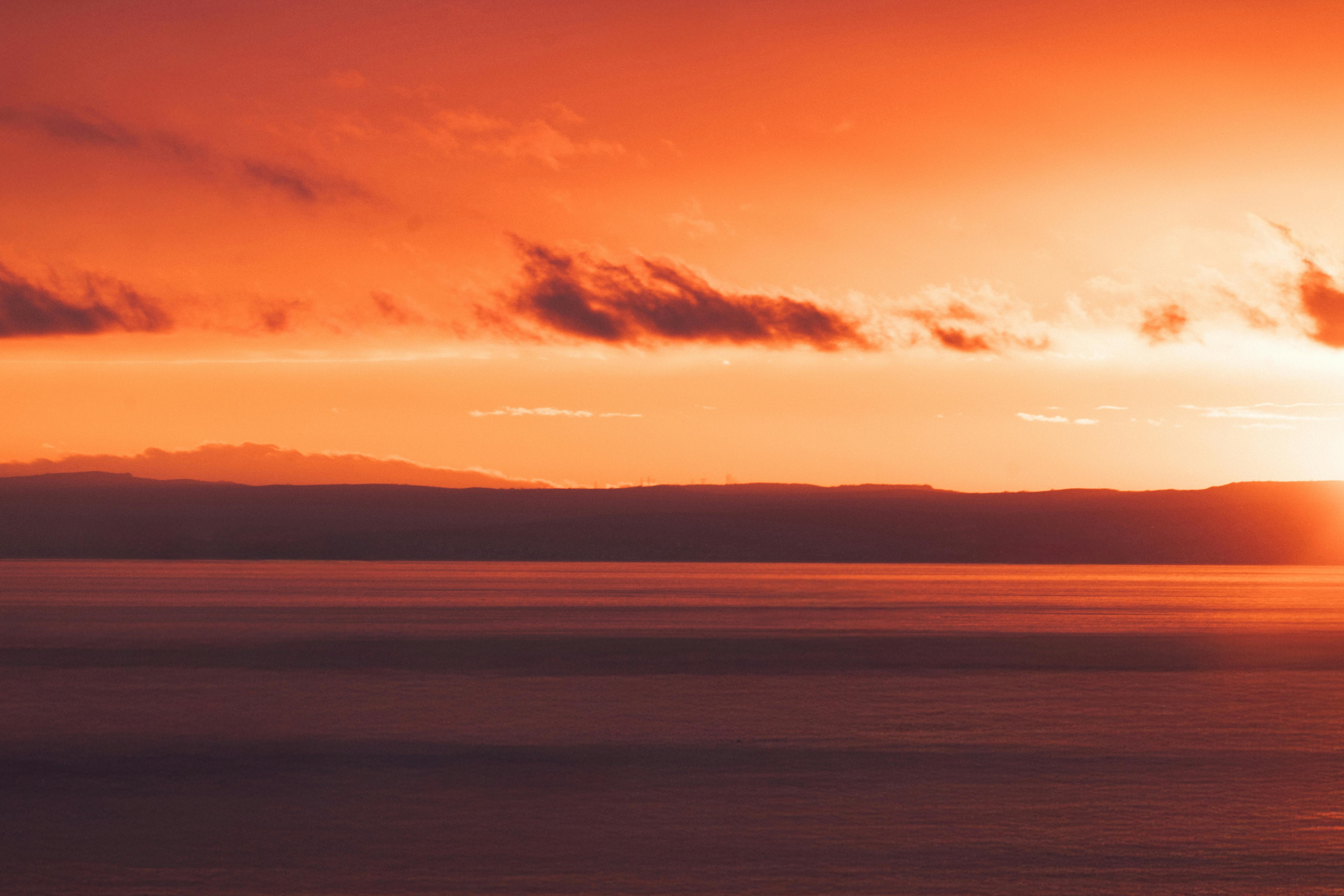 Bezpłatne Zachwycający zachód słońca nad spokojnym morzem, ukazujący przejście dnia w noc w żywych kolorach. Zdjęcie z galerii
