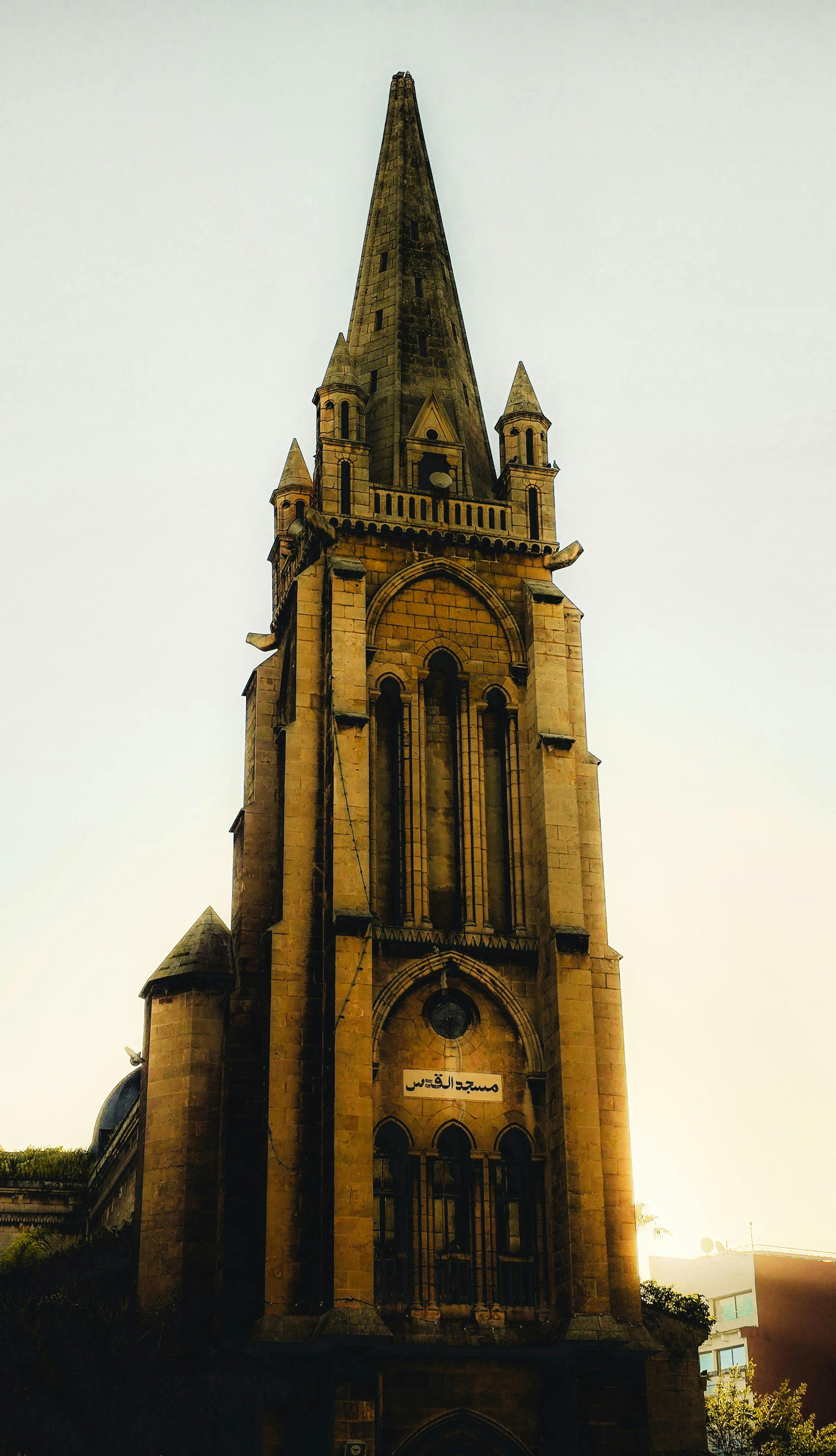 Gratis Et betagende kirketårn i nygotisk stil tårner sig op mod den klare himmel og indfanger arkitektonisk elegance. Lagerfoto