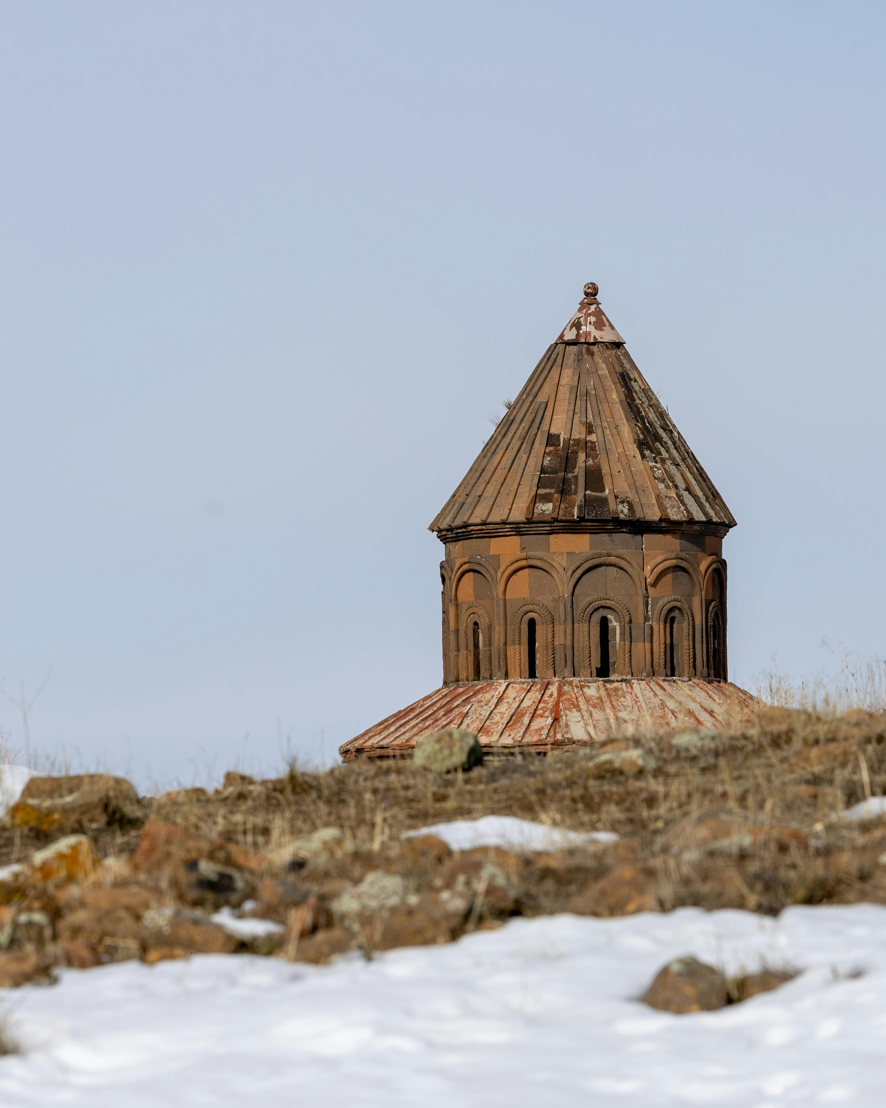 Gratis En historisk kirkekuppel i det sneklædte landskab i Kars, Tyrkiet, under en klar himmel. Lagerfoto