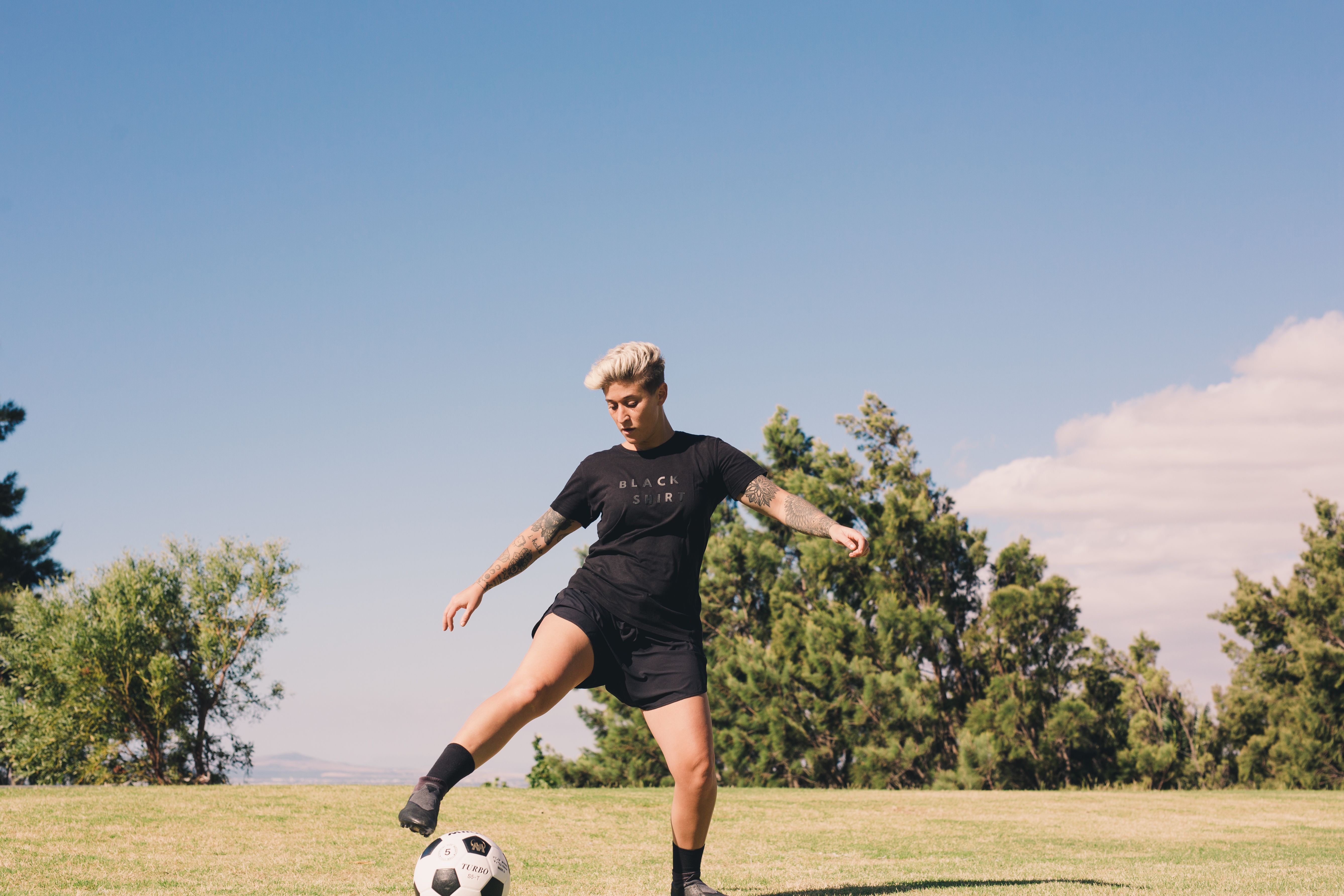 jogador-de-futebol-chutando-bola-de-futebol-cinza-branco-no-campo-de