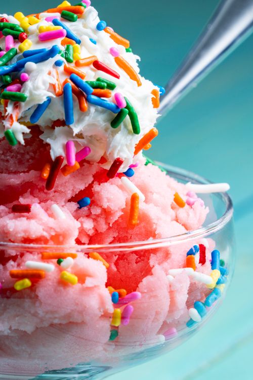 Free Close-up of a pink frozen dessert topped with whipped cream and colorful sprinkles in a glass bowl. Stock Photo
