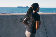 一位黑人妇女沿着海堤跑步，以促进健身和健康生活