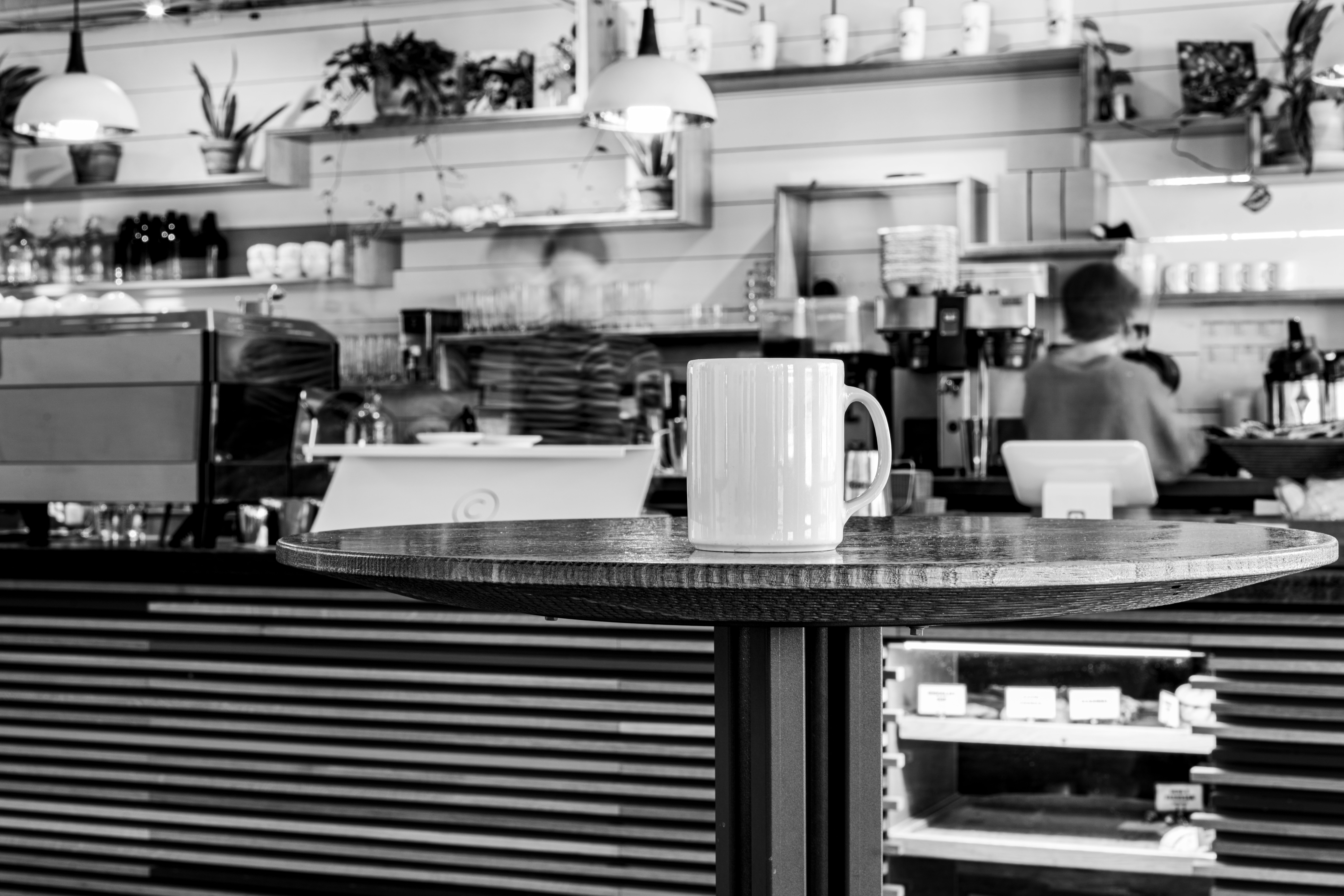 A black and white photo of a coffee shop interior featuring a mug on a table.