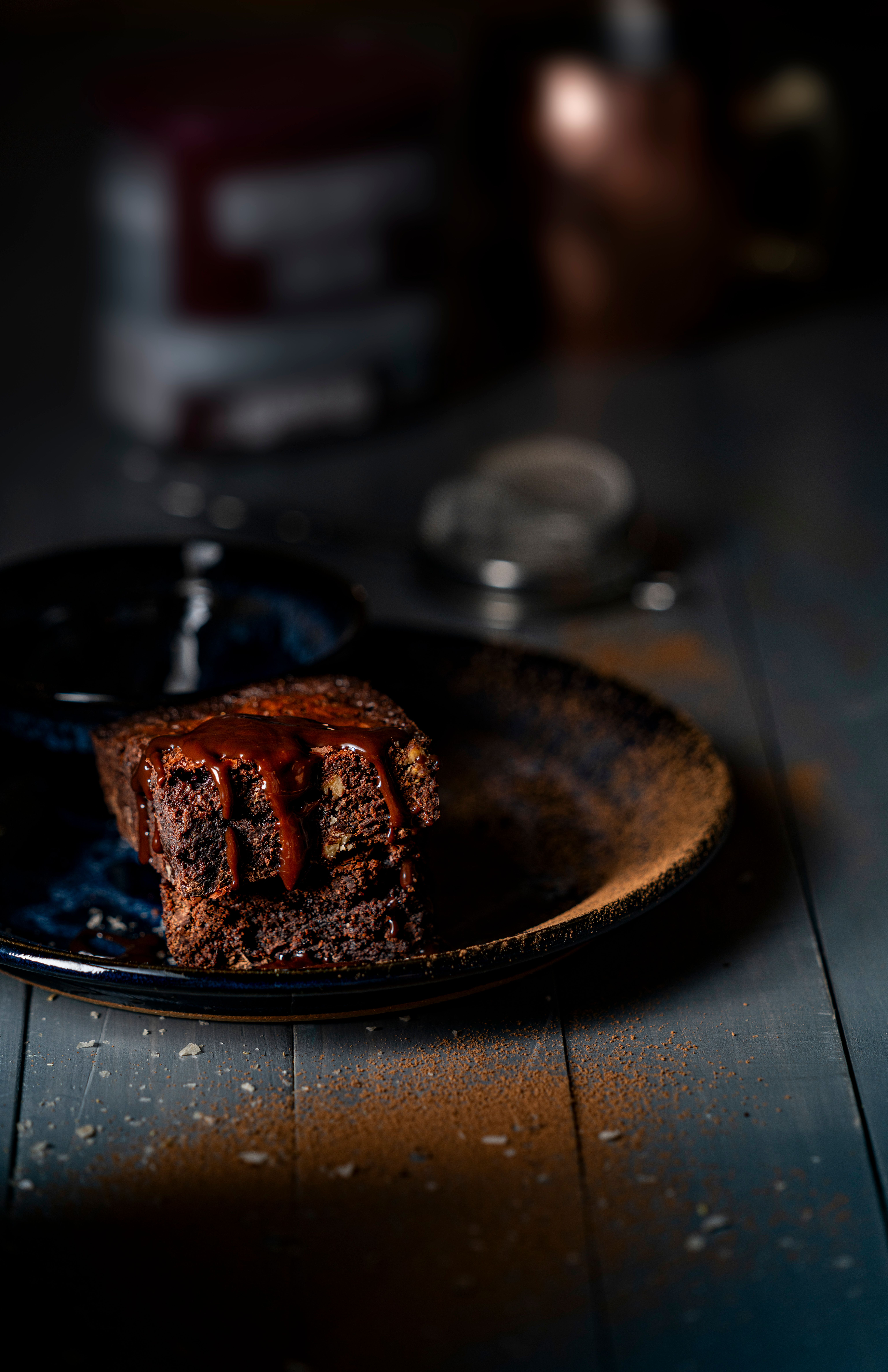 Mouthwatering chocolate brownie on a dark plate with a rich topping, perfect for gourmet food presentation.