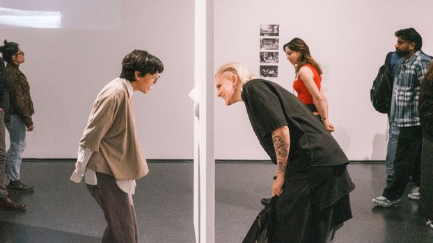 People engaging with art installation at an indoor exhibition.