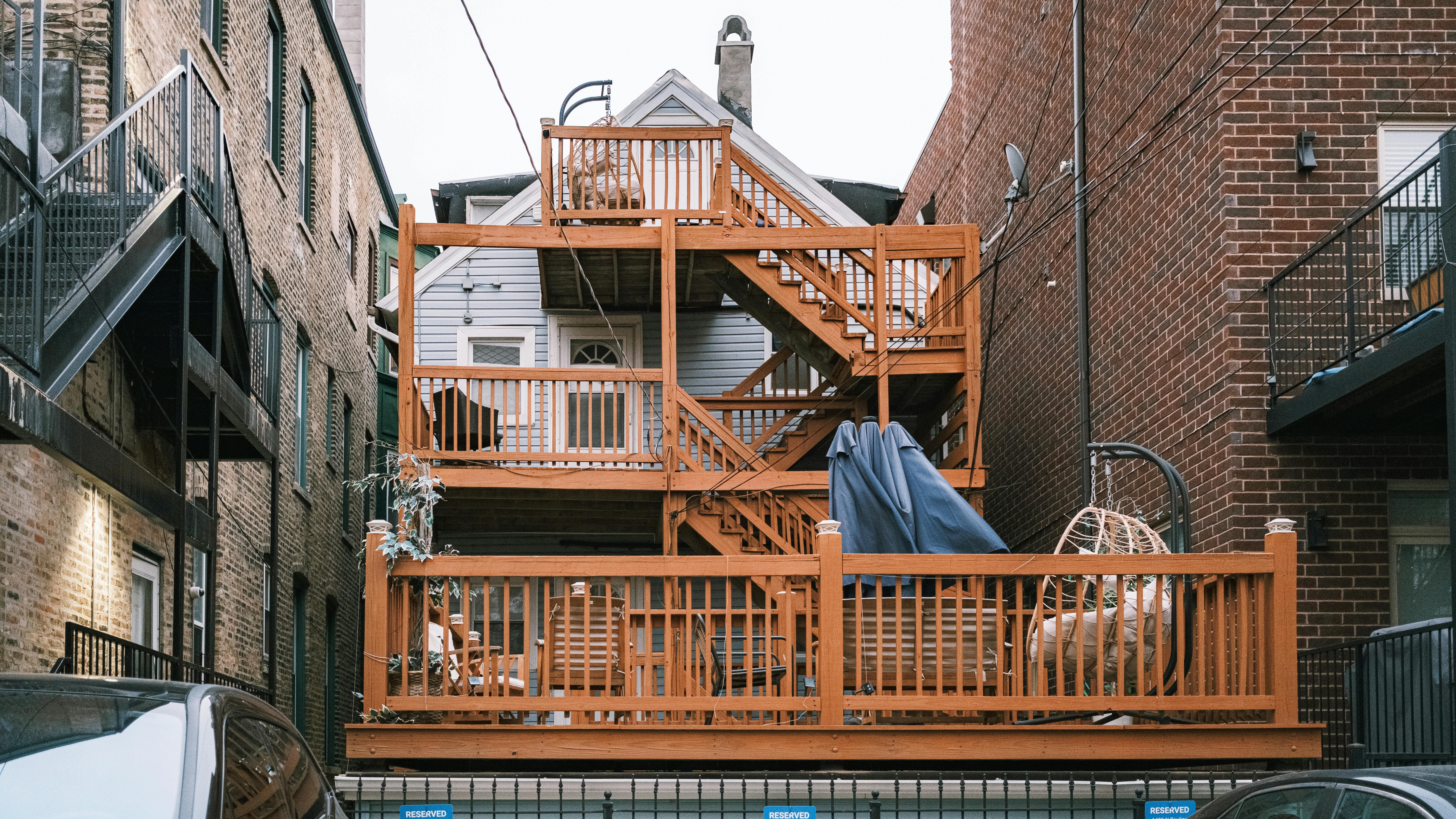 бесплатная Многоуровневая деревянная терраса между городскими зданиями, демонстрирующая уникальный архитектурный дизайн. Стоковое фото