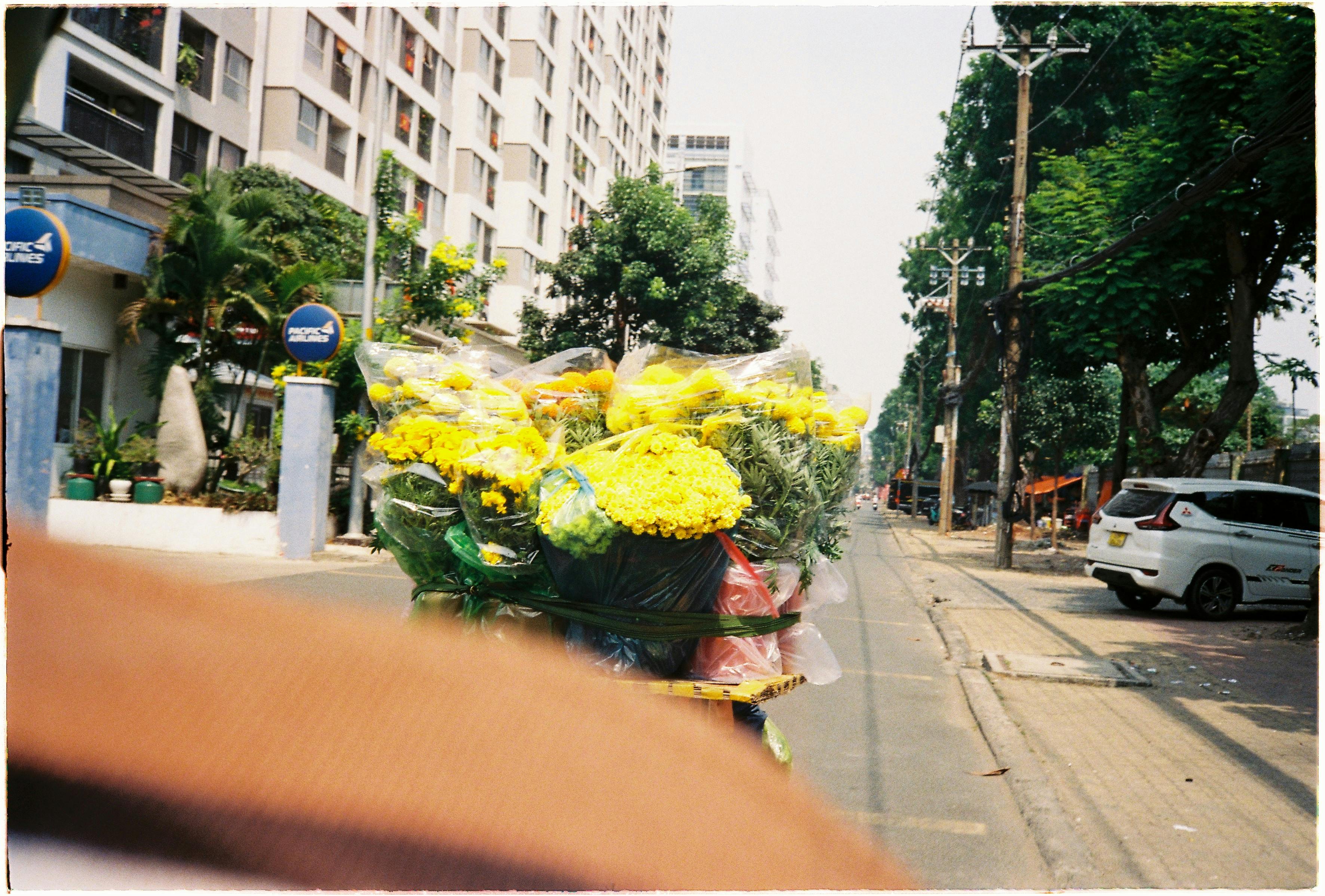 Bezpłatne Jaskrawo żółte kwiaty na rowerze ulicznego sprzedawcy w tętniącym życiem Ho Chi Minh City. Zdjęcie z galerii