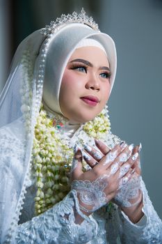 Close-up portrait of an Indonesian bride in traditional white attire and hijab.
