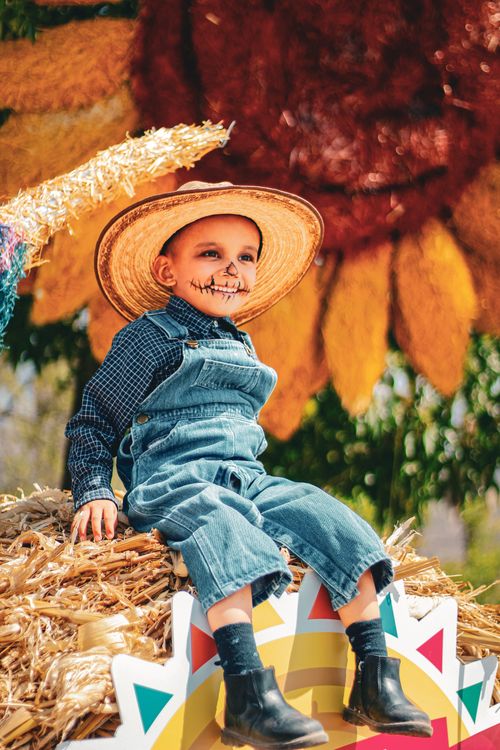 Free Smiling child with face paint, straw hat, and traditional outfit during Mexican festival outdoors. Stock Photo