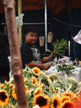 A florist arranging fresh sunflowers at an outdoor market stall, creating a vibrant display.