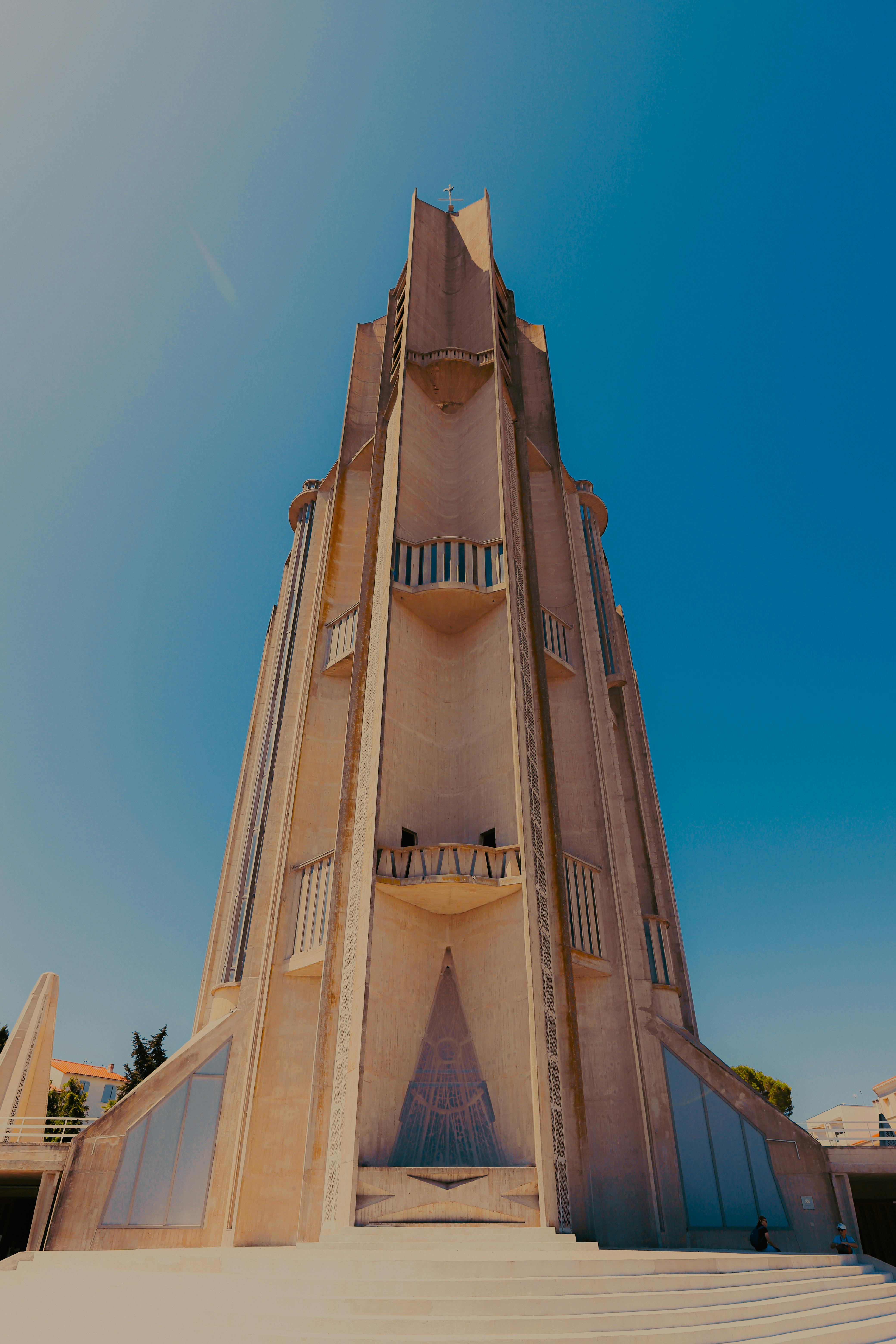 Kostenlos Ein hoch aufragendes, modernes Bauwerk mit geometrischer Formgebung vor einem klaren blauen Himmel. Stock-Foto