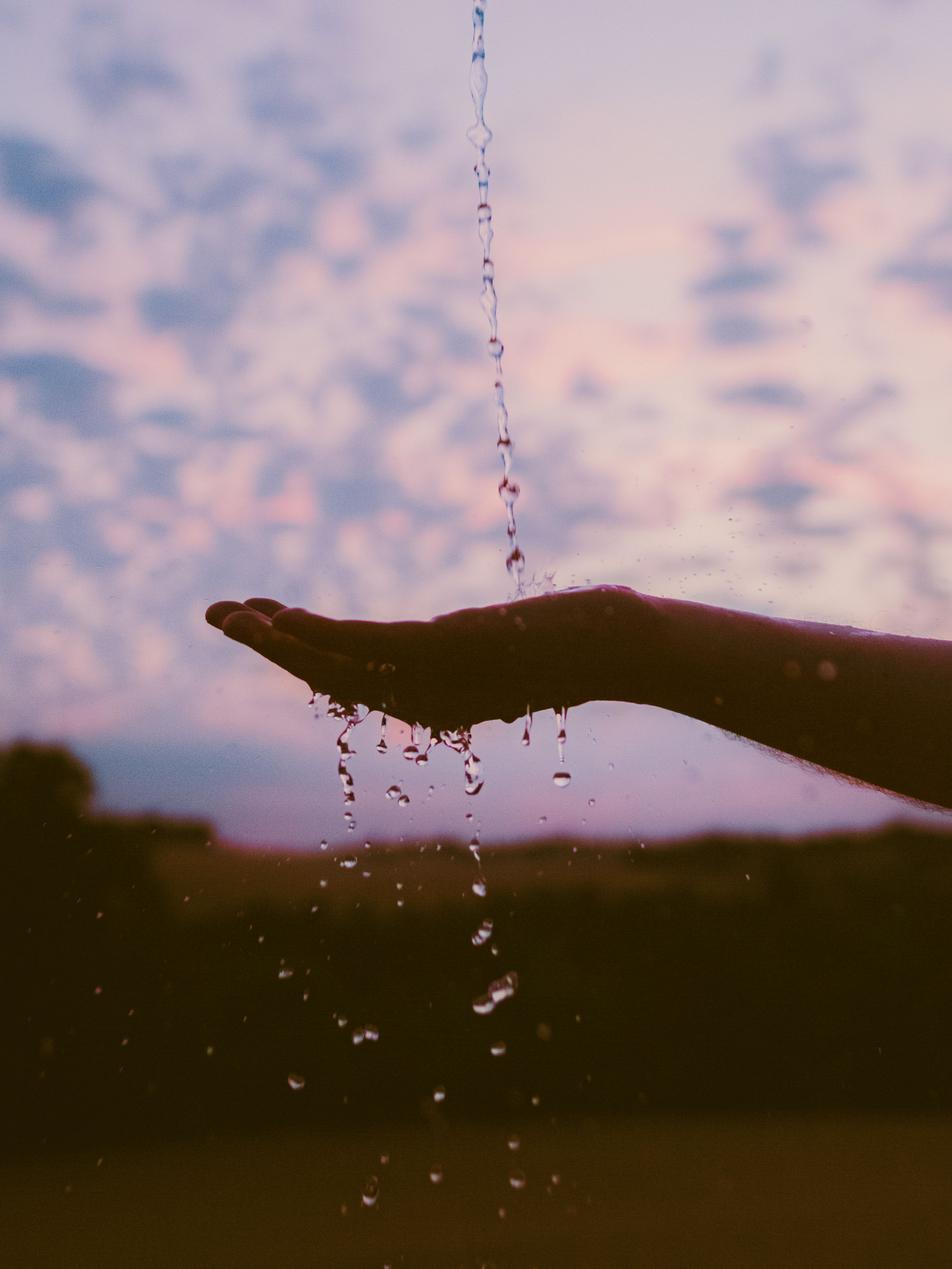 Silhouette of Hand Catching Dripping Water at Sunset · Free Stock Photo
