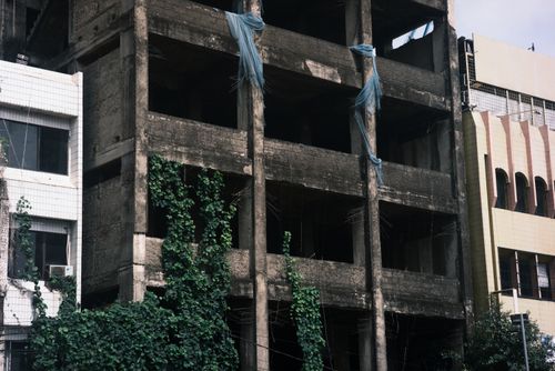 Free Crumbling unfinished building with overgrown plants in urban setting. Stock Photo