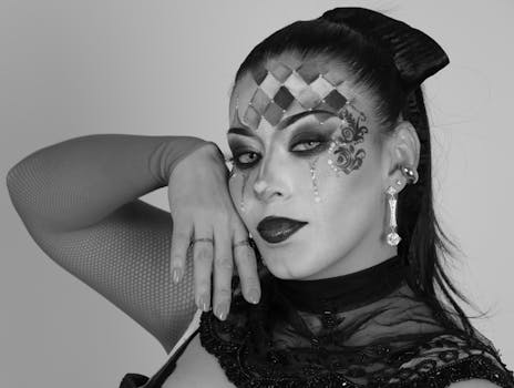 Intricate black and white makeup portrait featuring a unique harlequin design and jewelry accents.