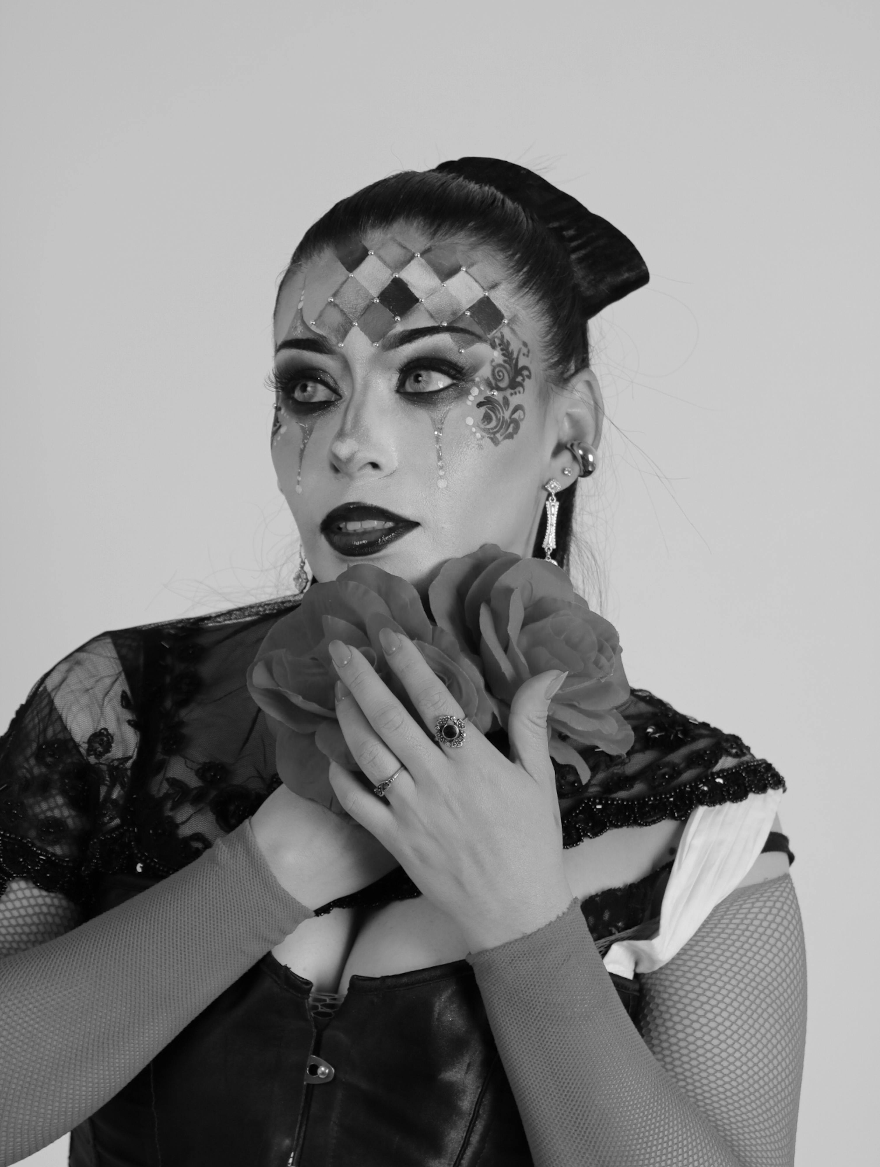 Bezpłatne Ekspresyjny portret arlekina z dramatycznym makijażem i artystycznym kostiumem w czerni i bieli. Zdjęcie z galerii