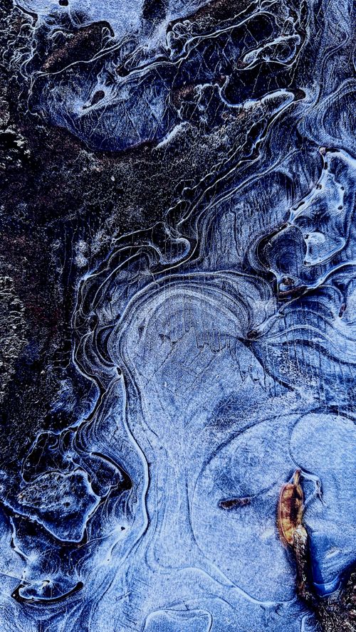 Free Aerial view of intricate ice patterns in shades of blue resembling an abstract painting. Stock Photo