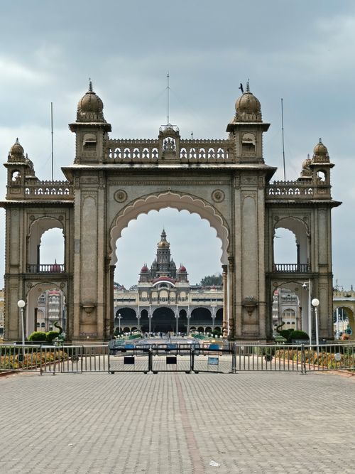 Free The grand entrance of Mysore Palace, showcasing its intricate architecture under a cloudy sky. Stock Photo
