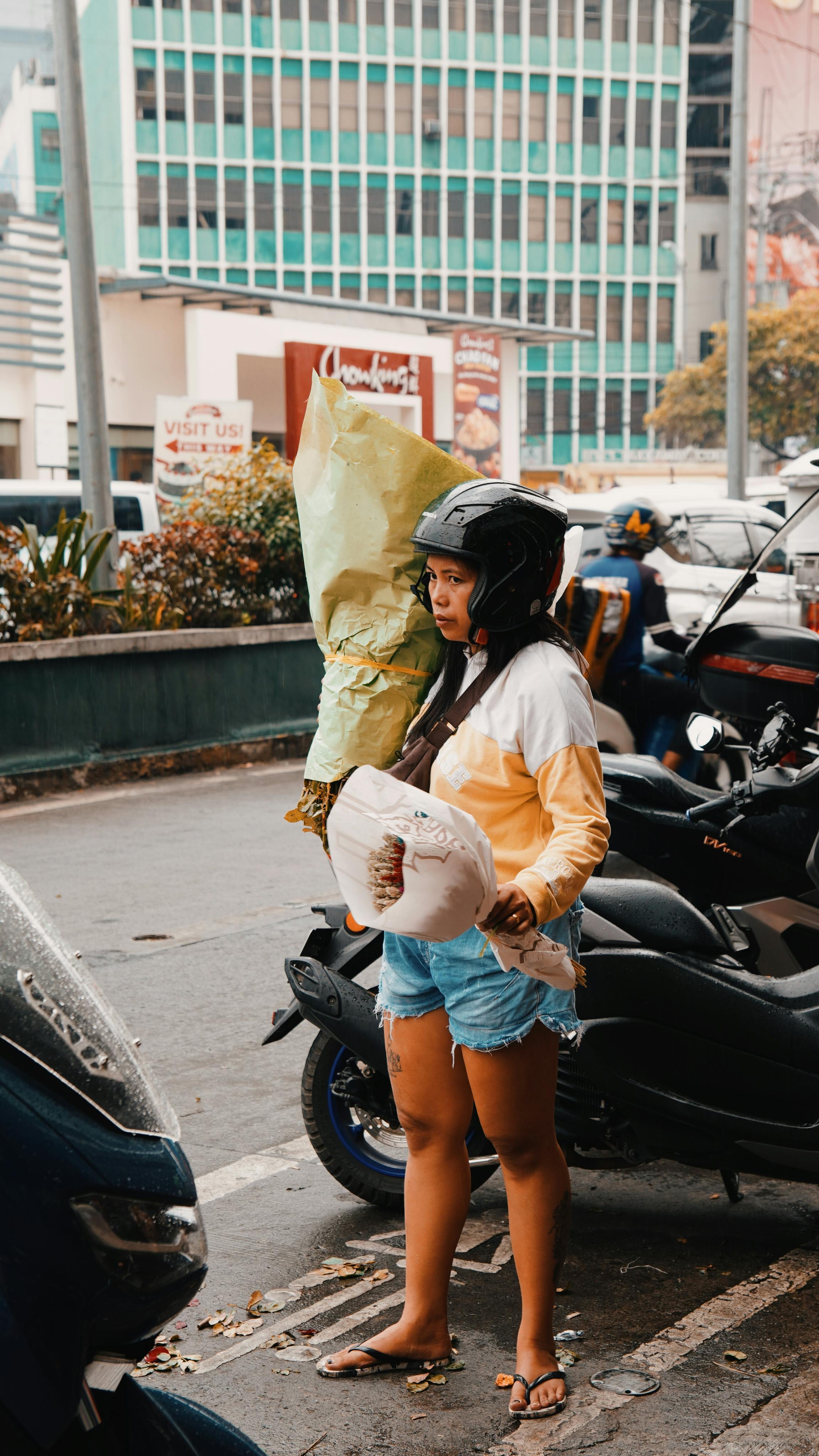 Gratuit Femeie stând pe stradă cu buchet și geantă într-un cadru urban. Fotografie de stoc