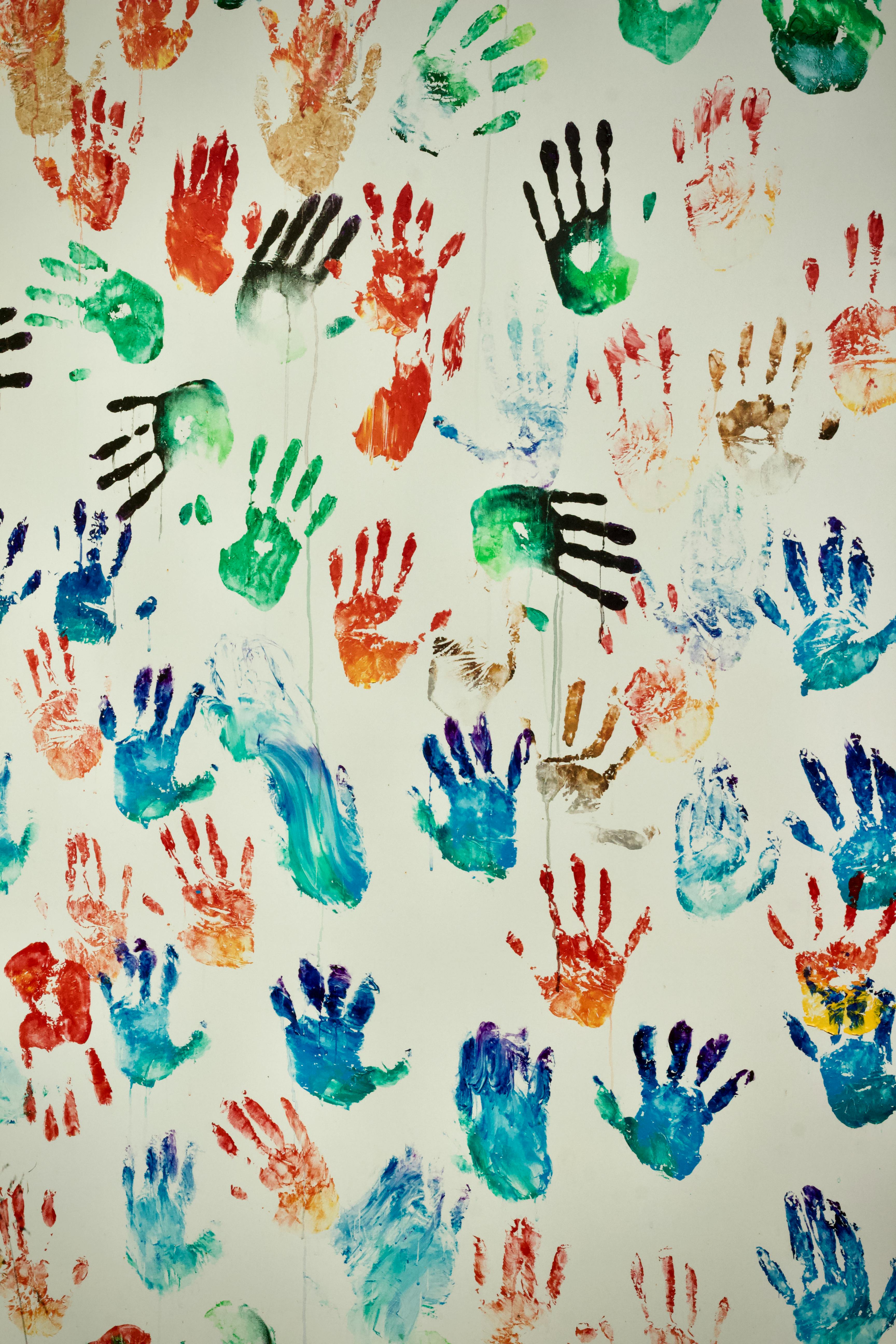 Bezpłatne Żywe odciski dłoni w różnych kolorach na białej ścianie tworzą wesołą, artystyczną scenę. Zdjęcie z galerii