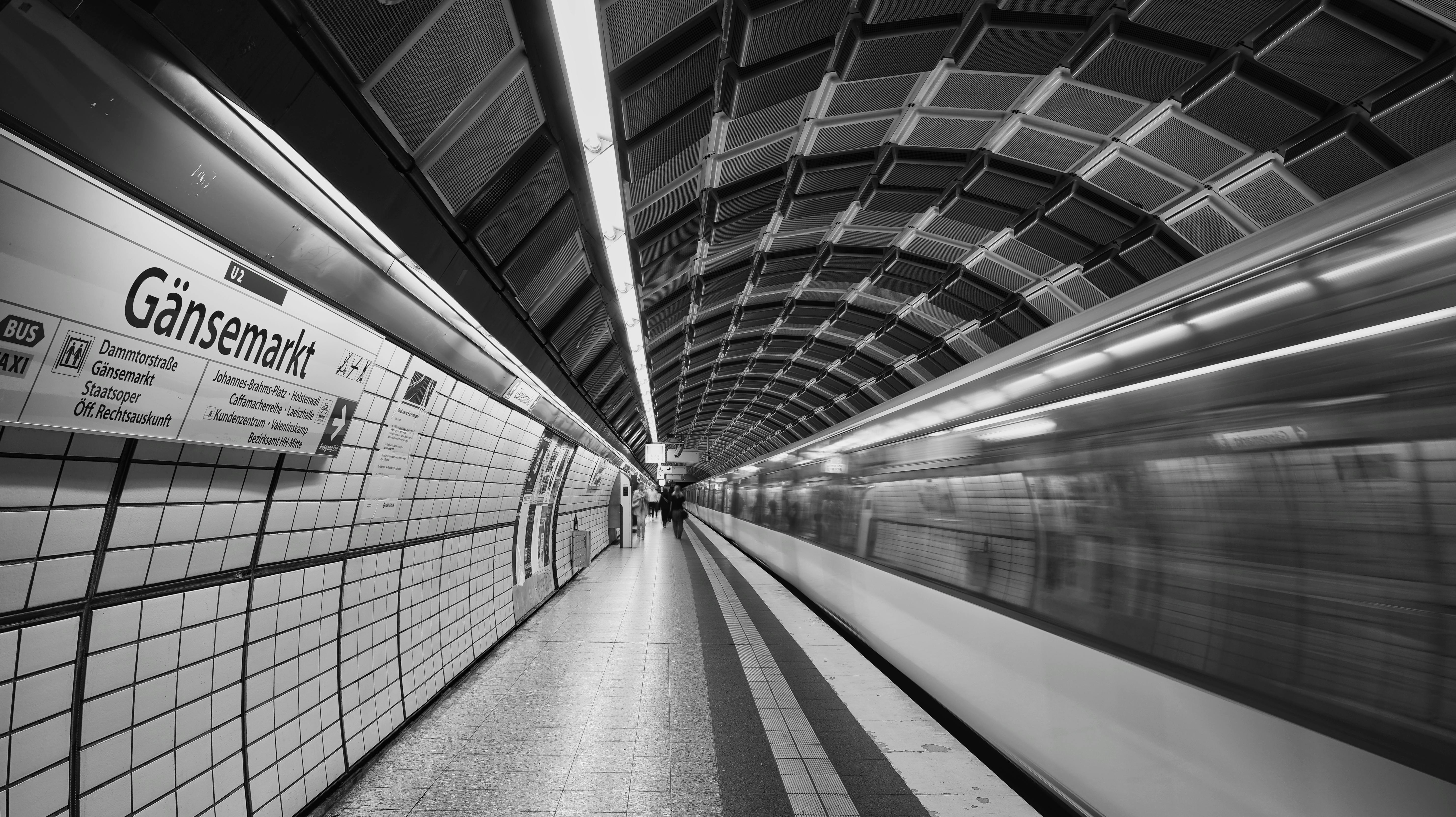 Gratis Et hurtigtkørende tog på Hamborgs Gänsemarkt metrostation, fanget i sort-hvid. Lagerfoto