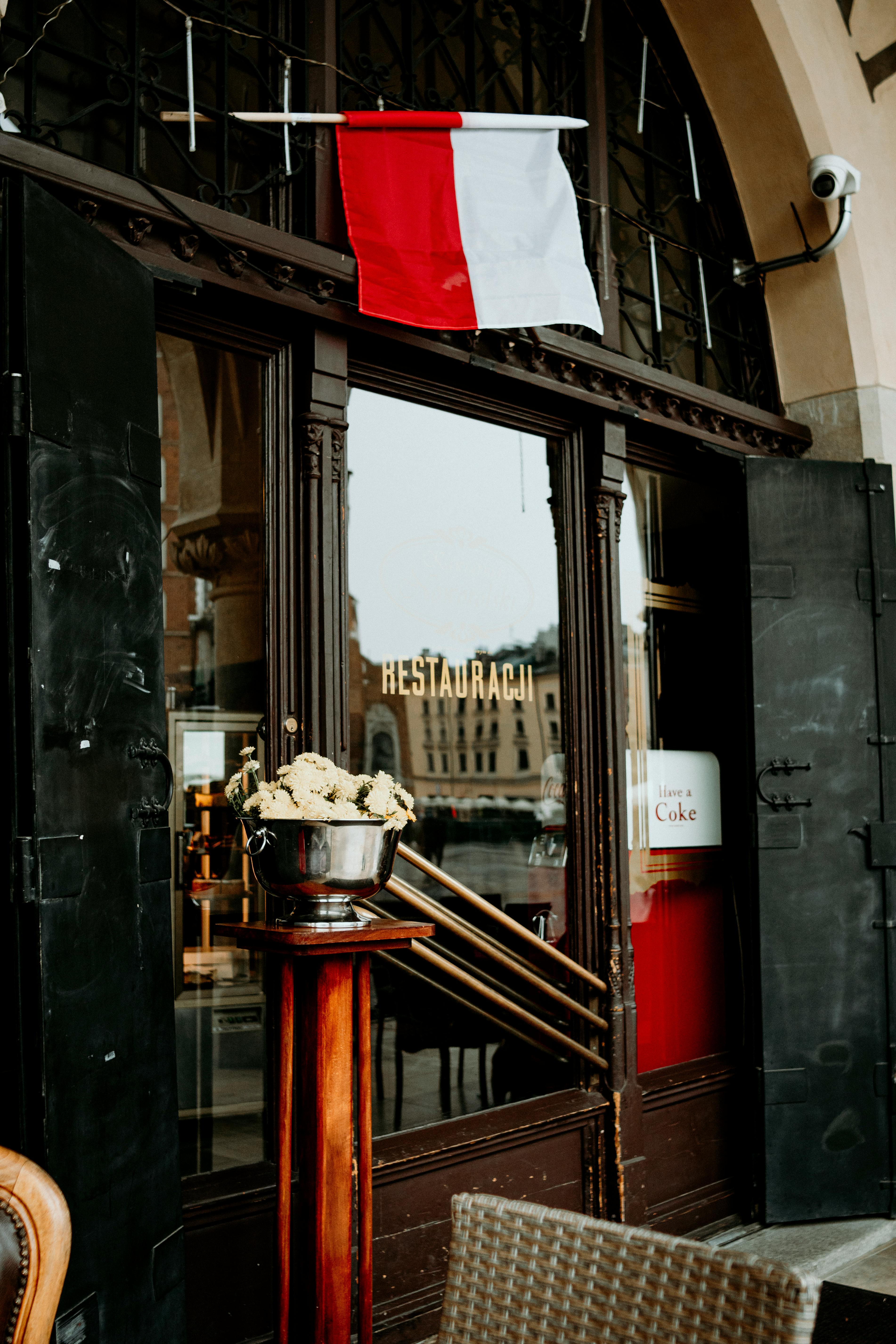 Gratis Smuk restaurantindgang i Krakow med polsk flag og elegant arkitektur, en indbydende atmosfære for spisende gæster. Lagerfoto