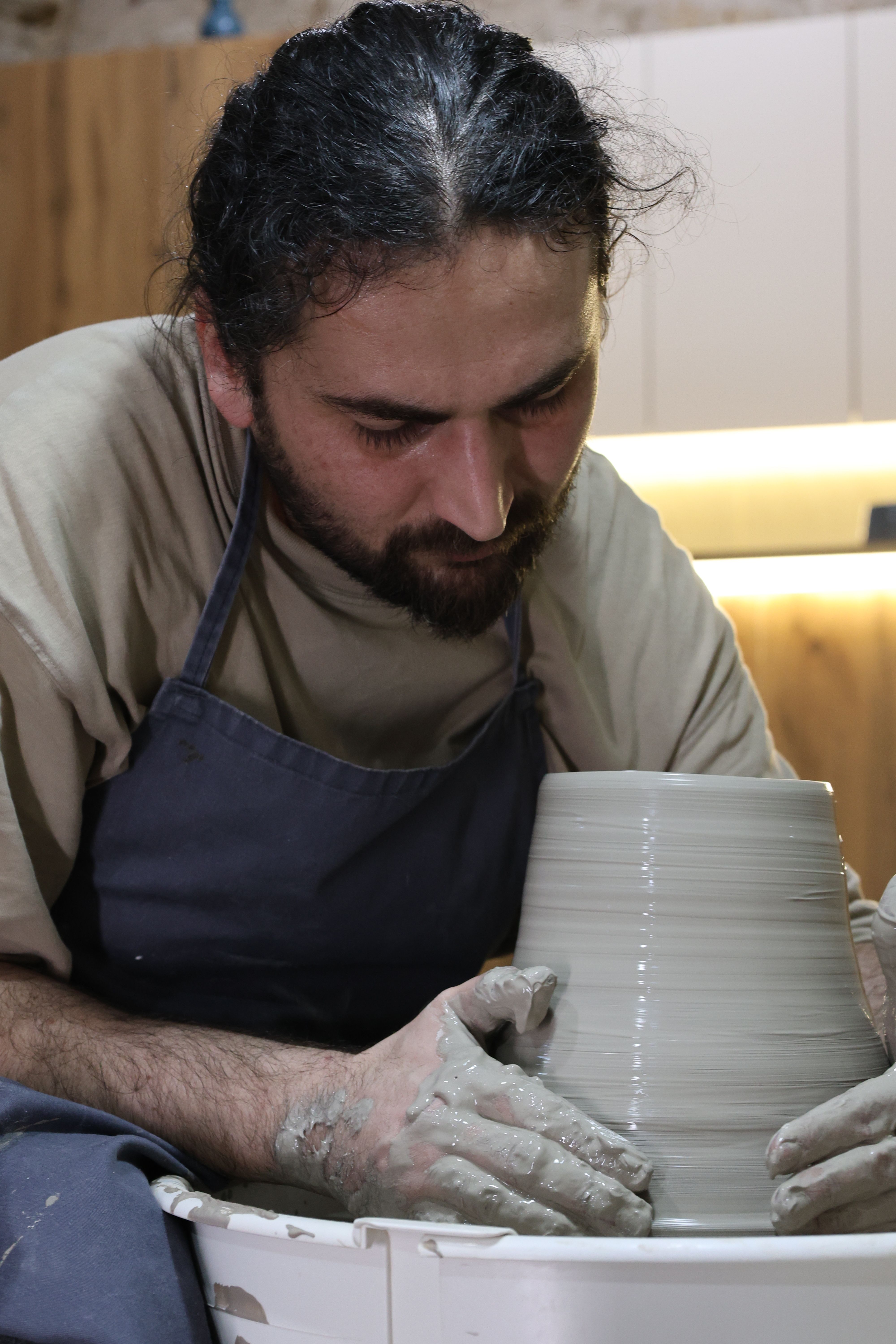 Man Crafting Pottery Indoors at Night