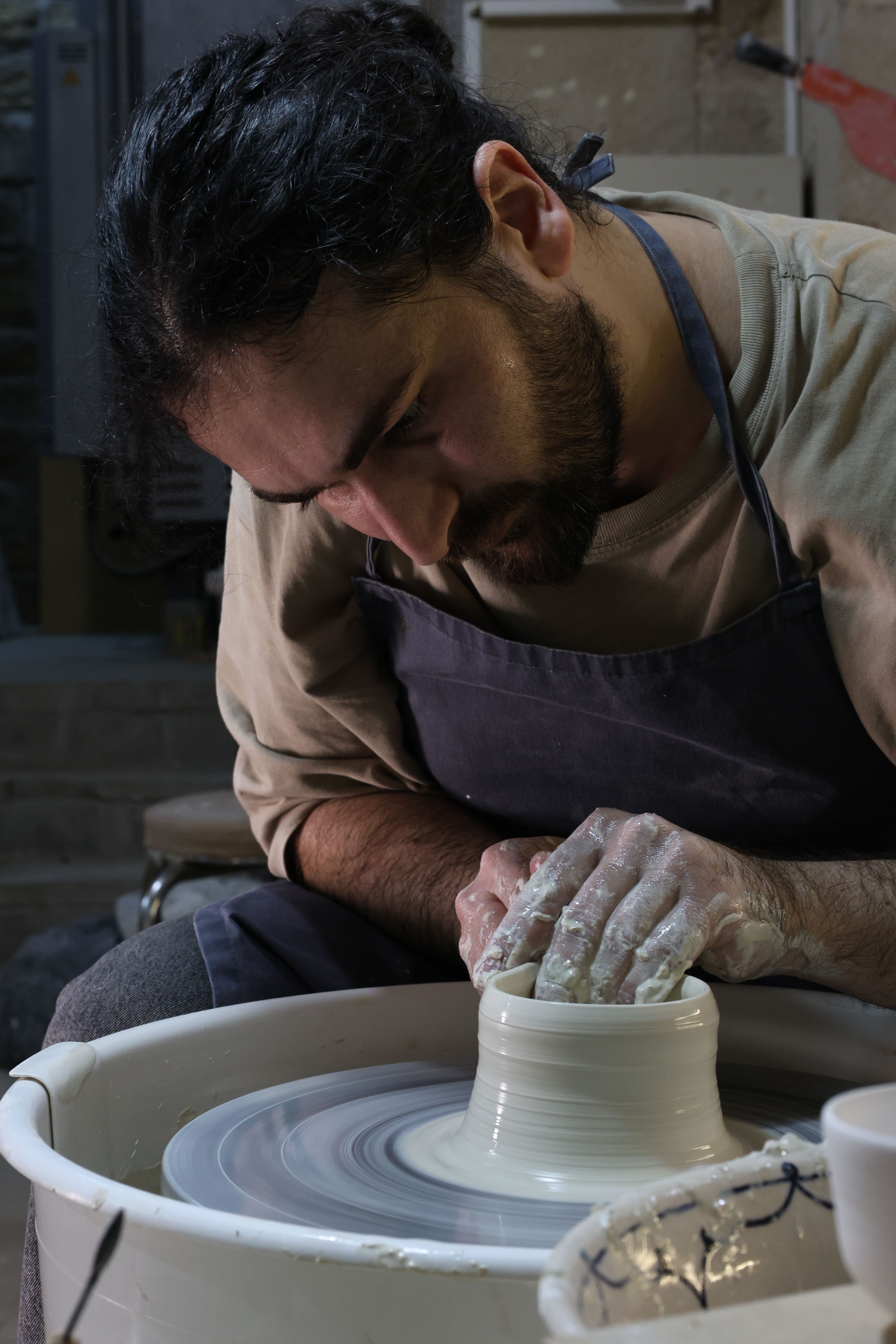 Focused Potter Crafting on Wheel in Studio