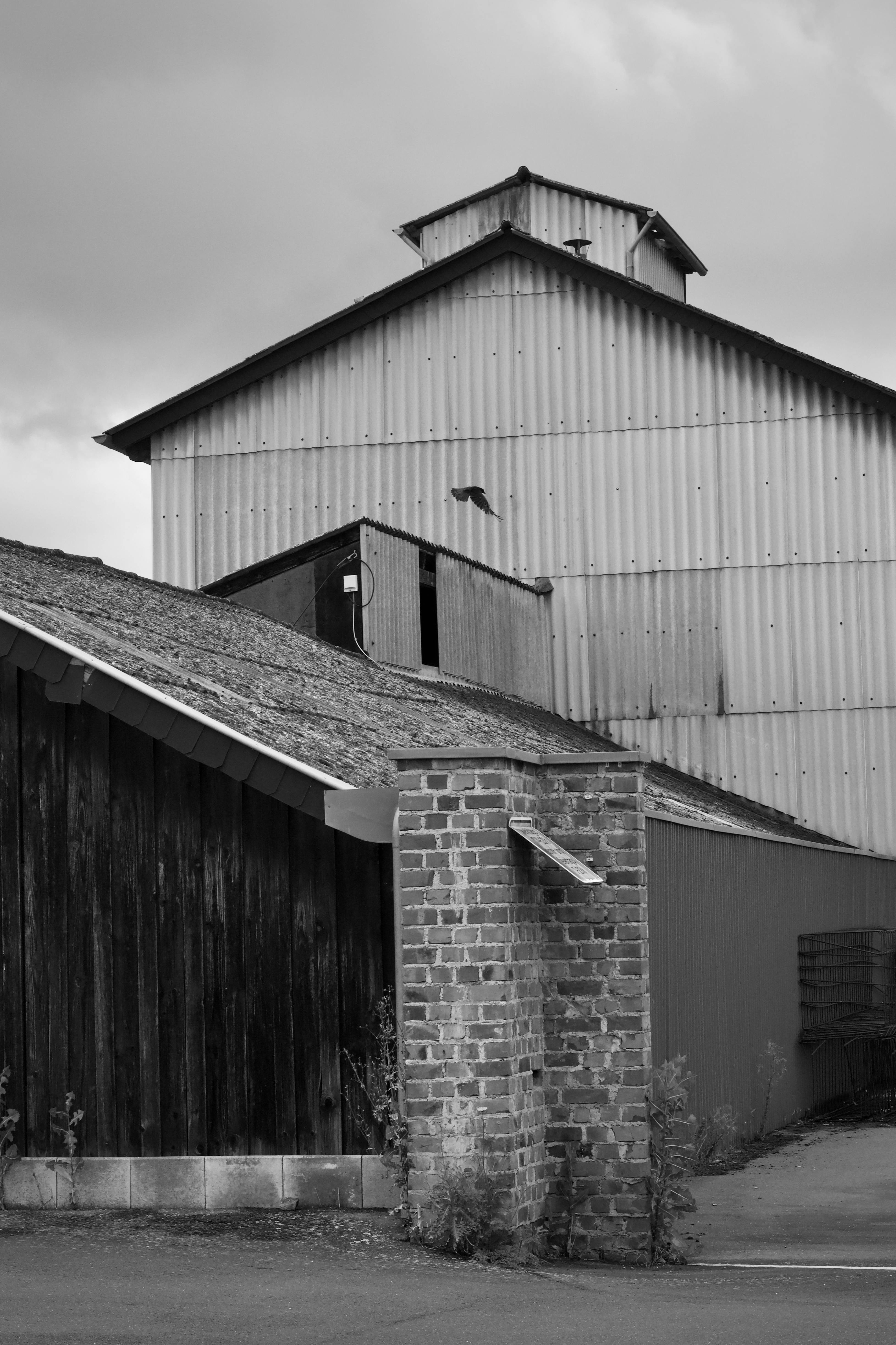 Δωρεάν Ατμοσφαιρική ασπρόμαυρη φωτογραφία ενός αγροτικού βιομηχανικού κτιρίου με στοιχεία από τούβλα και μέταλλο. Φωτογραφία από στοκ φωτογραφιών