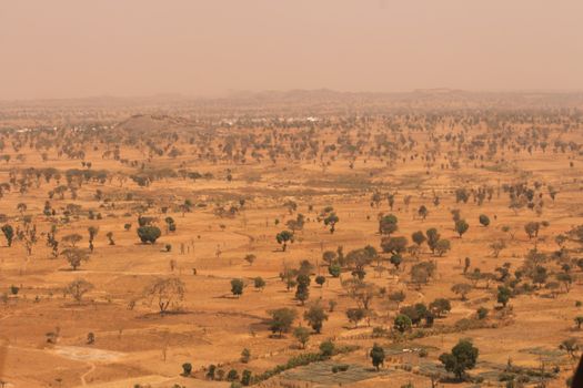 Aerial view capturing the dry, expansive landscape of Kaduna, Nigeria in warm tones.