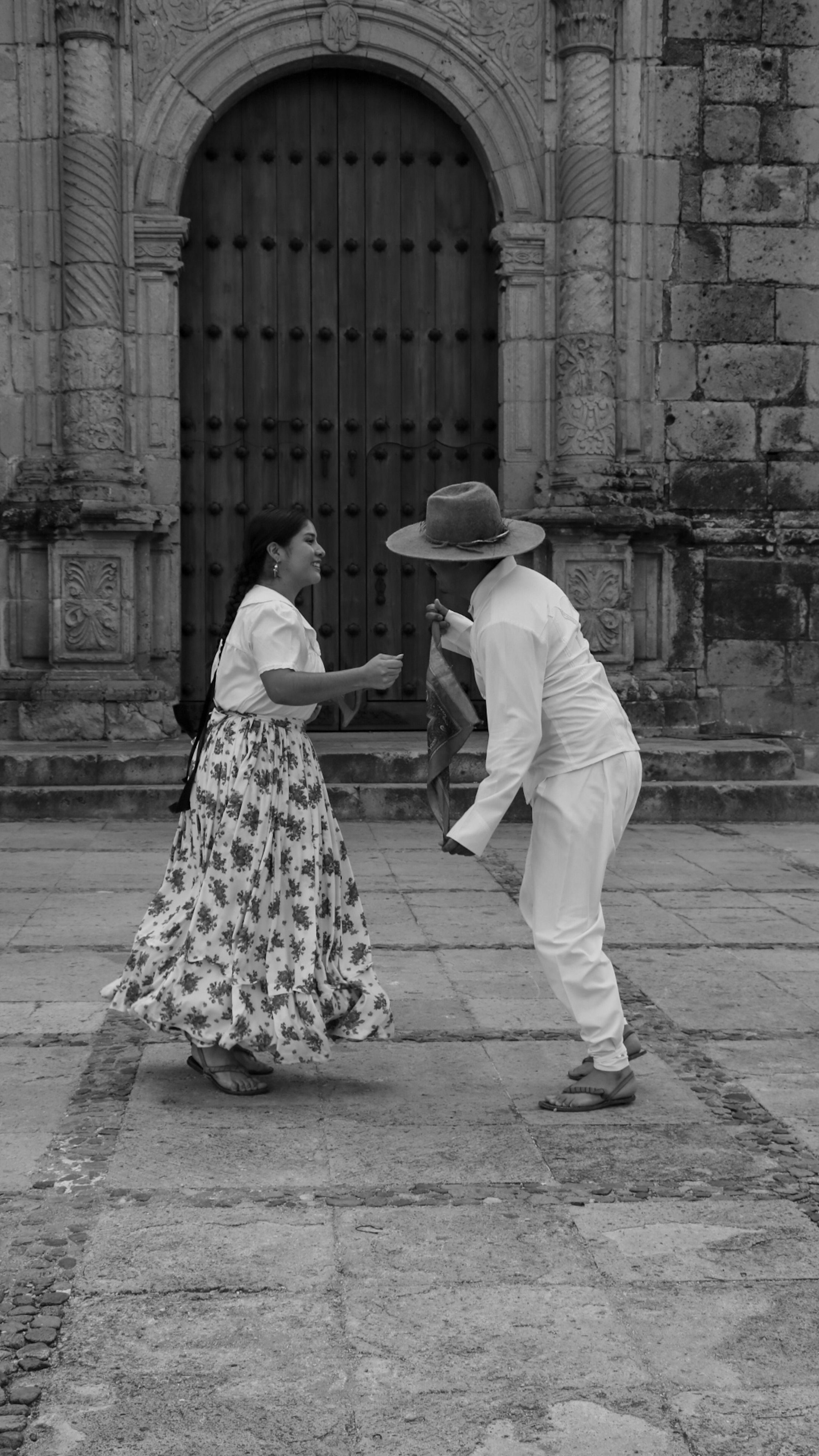 A couple dances passionately in front of an ancient stone doorway, showcasing cultural heritage.