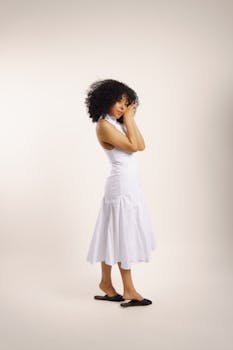 Elegant woman in white dress posing in a minimalist studio setting