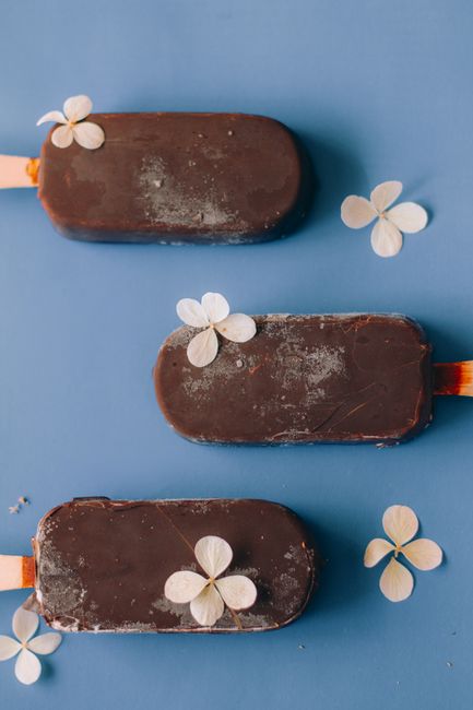Delicious chocolate ice cream bars decorated with delicate white flowers on a blue background.