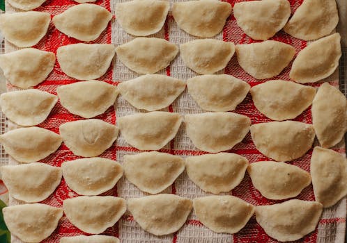 Top view of freshly made dumplings arranged neatly on a red checkered cloth.