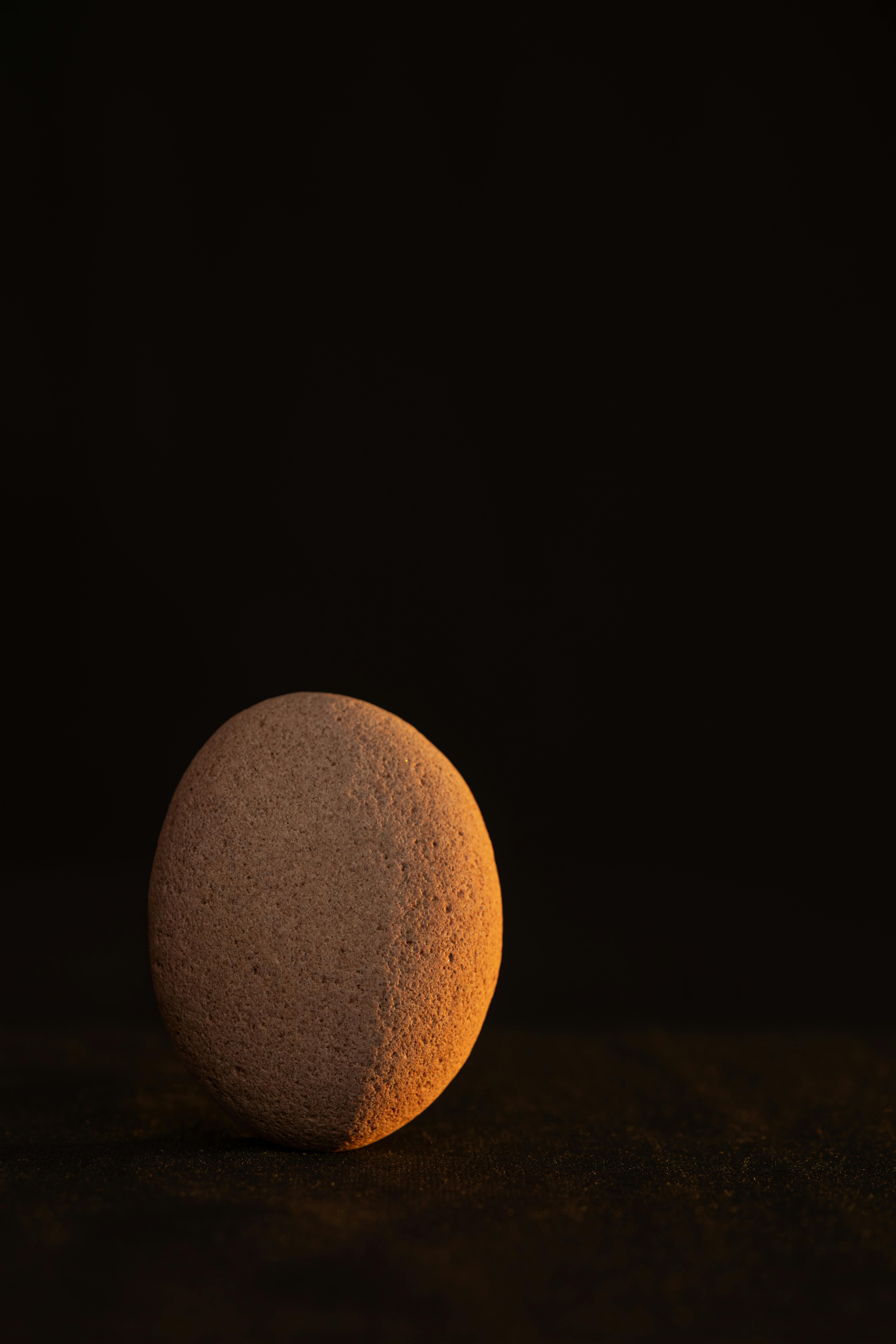 Gratuit O singură piatră zen iluminată pe un fundal întunecat, proiectând calm și echilibru. Fotografie de stoc