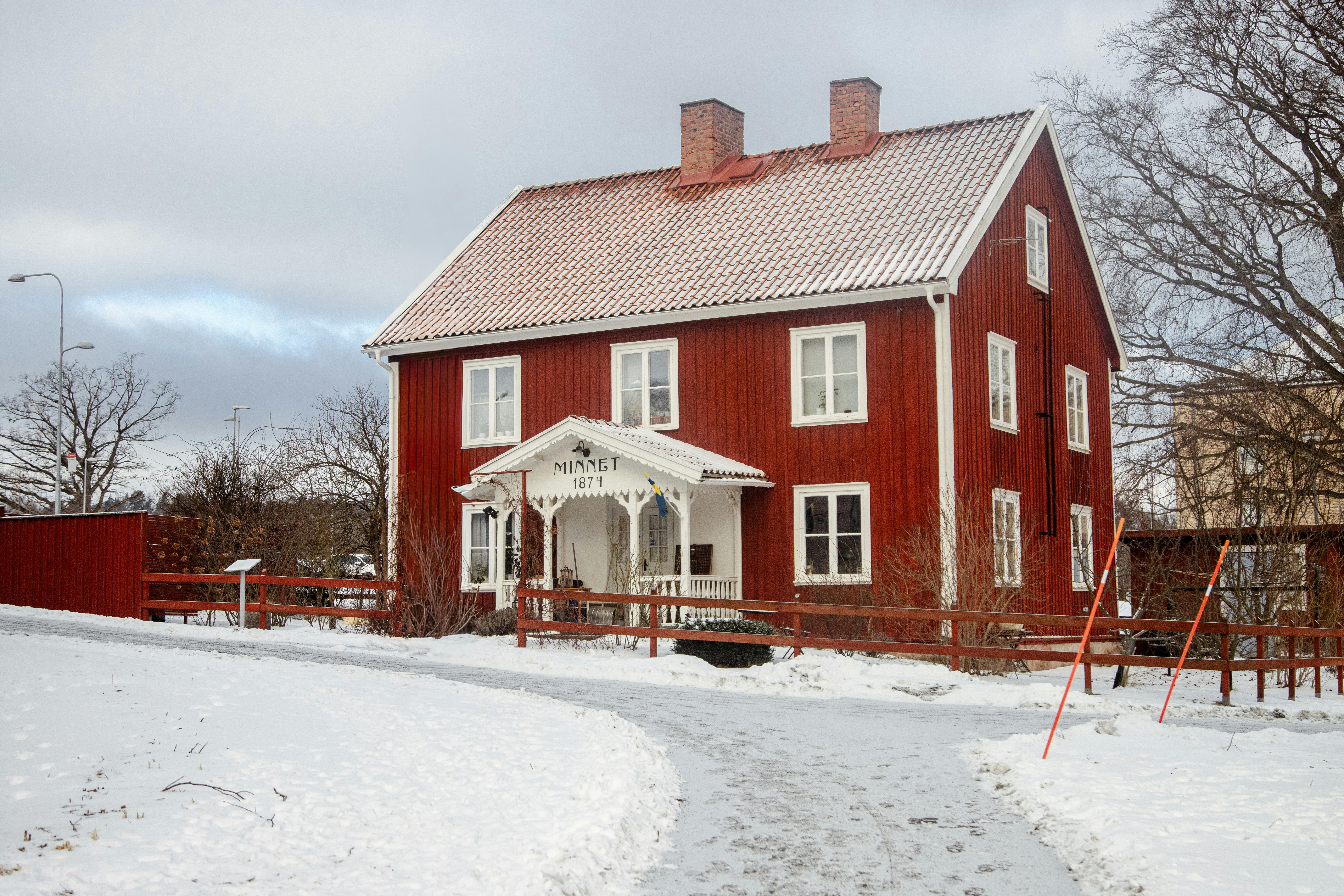 бесплатная Очаровательный красный деревянный домик на фоне заснеженного зимнего пейзажа, Йёнчёпинг, Швеция. Стоковое фото