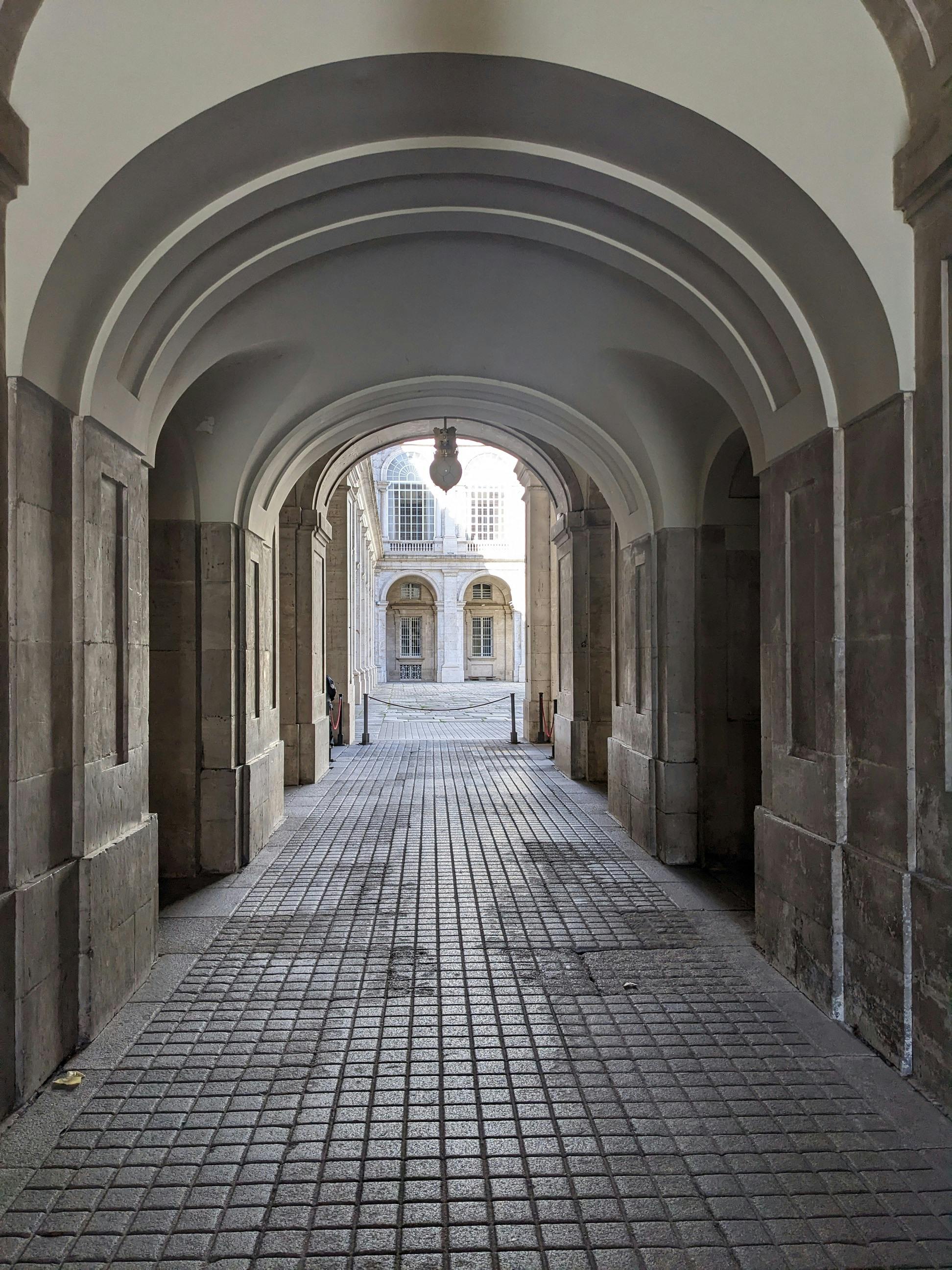 Gratis Elegant stenkorridor med buegange, der fører til den historiske gårdsplads. Arkitektonisk skønhed og symmetri. Lagerfoto