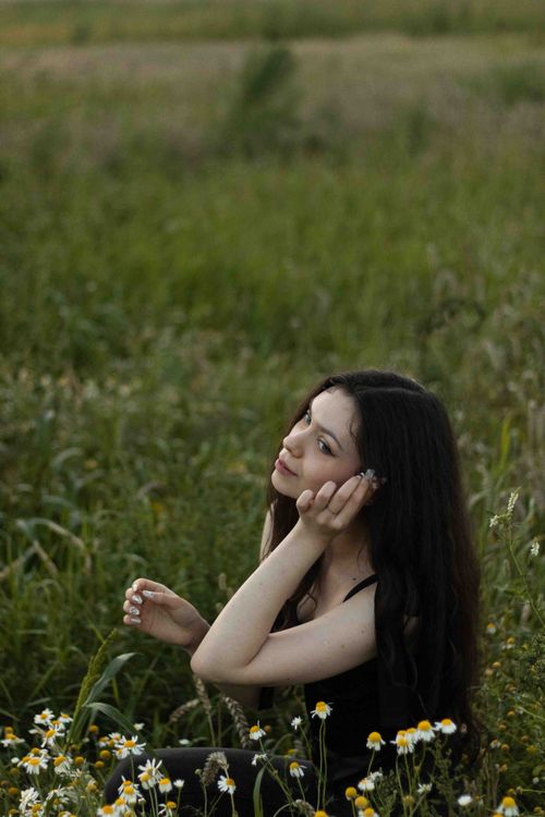 Free A serene portrait of a young woman in a field of daisies at dusk, embracing nature. Stock Photo