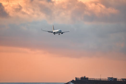 Airplane approaching for landing against a vibrant Bali sunset sky.